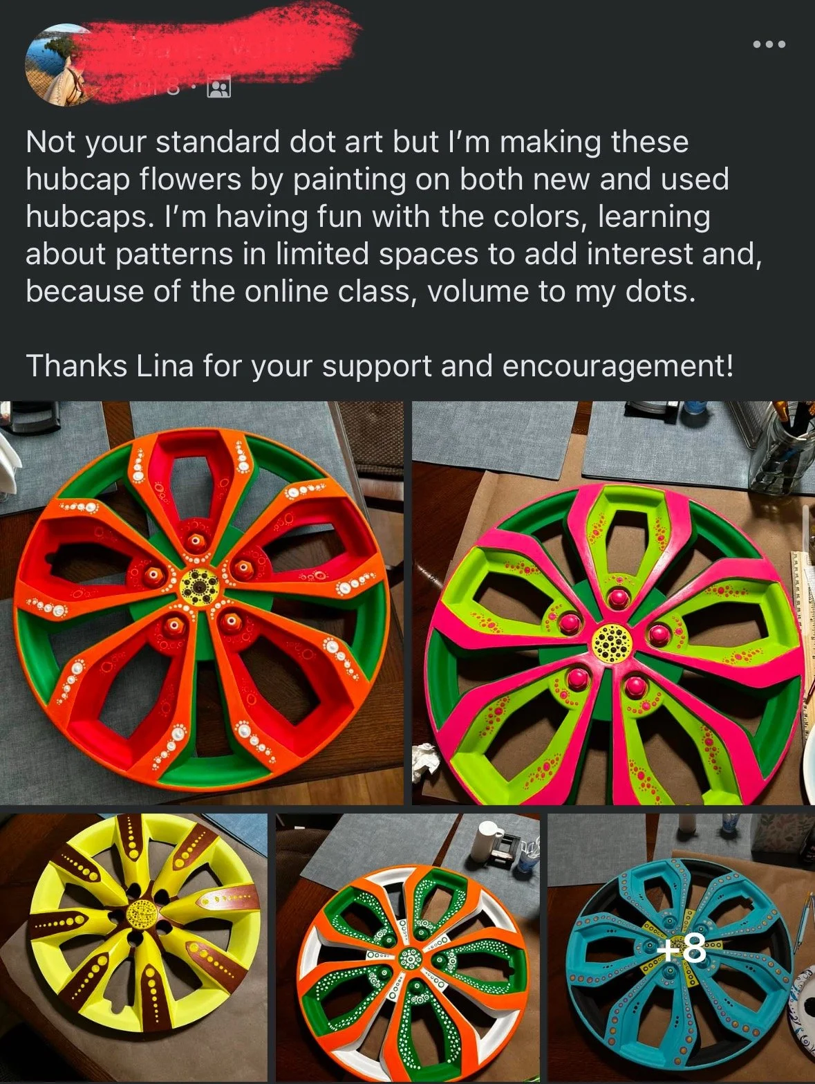 Colorful painted hubcap flowers on a table, each hubcap painted with different patterns and colors, resembling flower petals.