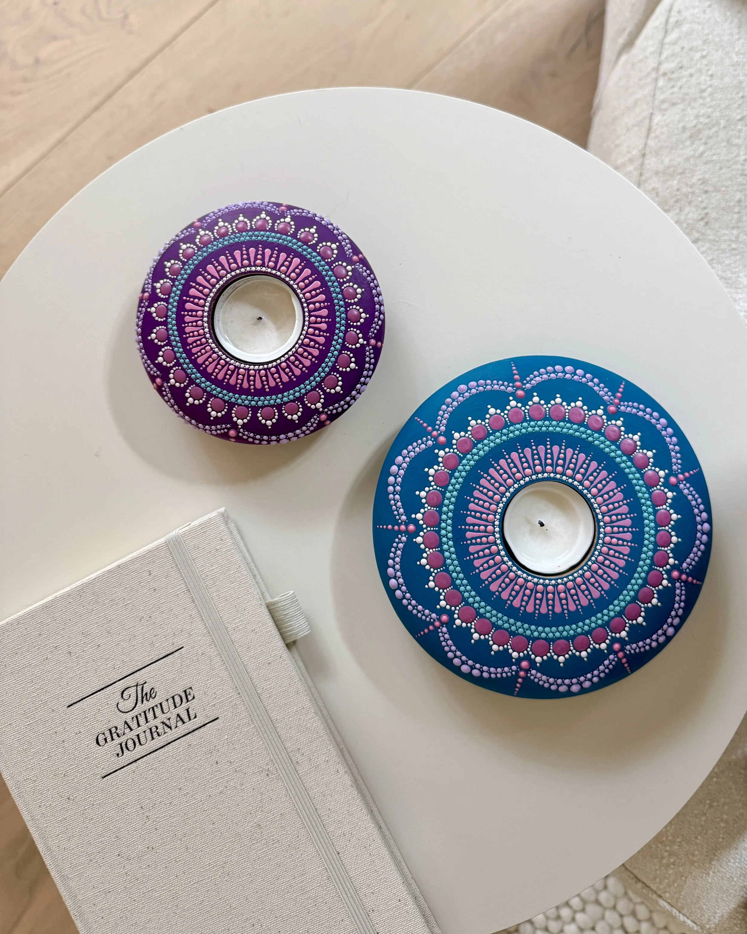 Decorative painted circular objects with pink, blue, and white dotted patterns on a white surface.