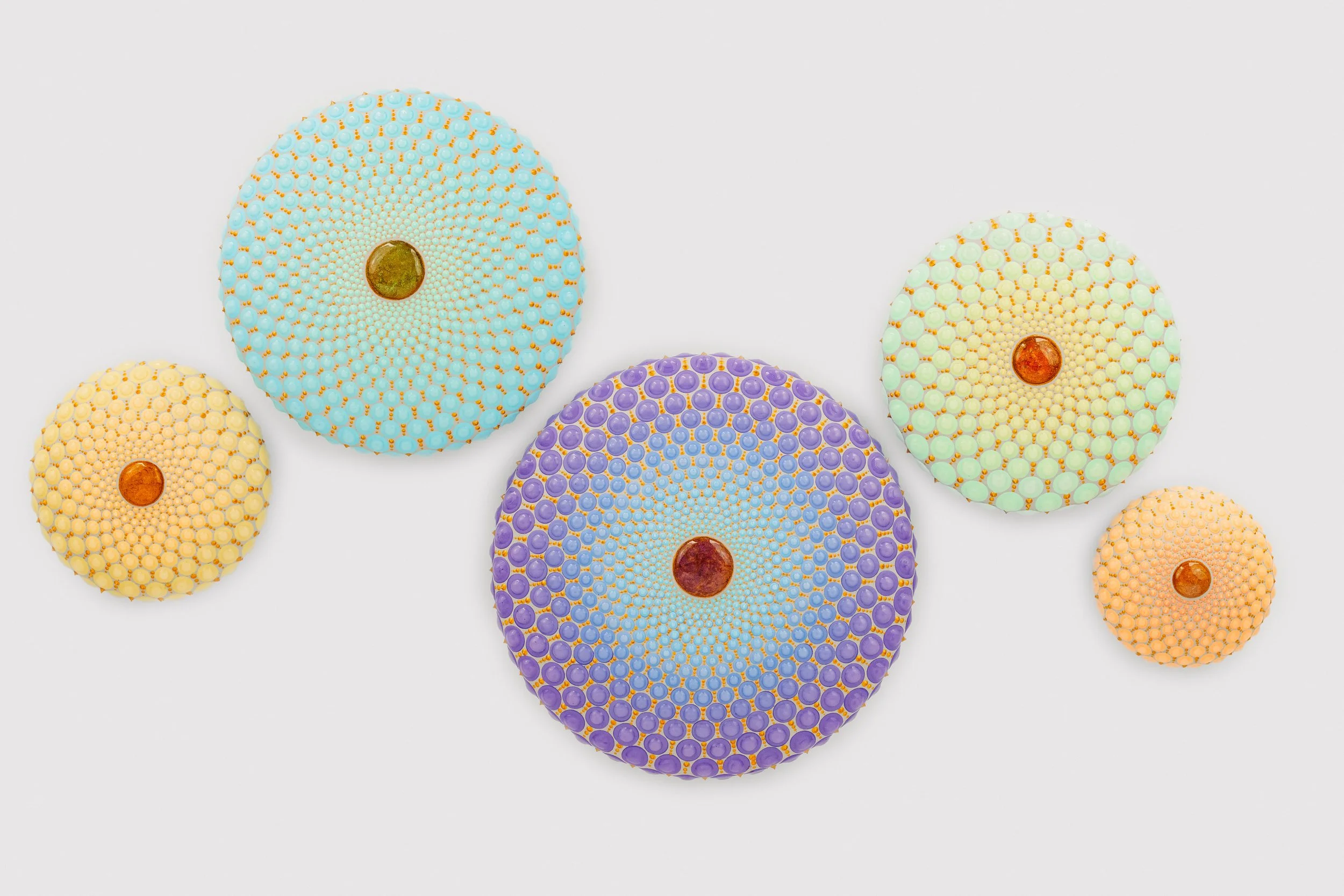 Colorful mosaic wall art with circular patterns in shades of blue, purple, yellow, and green on a white background.