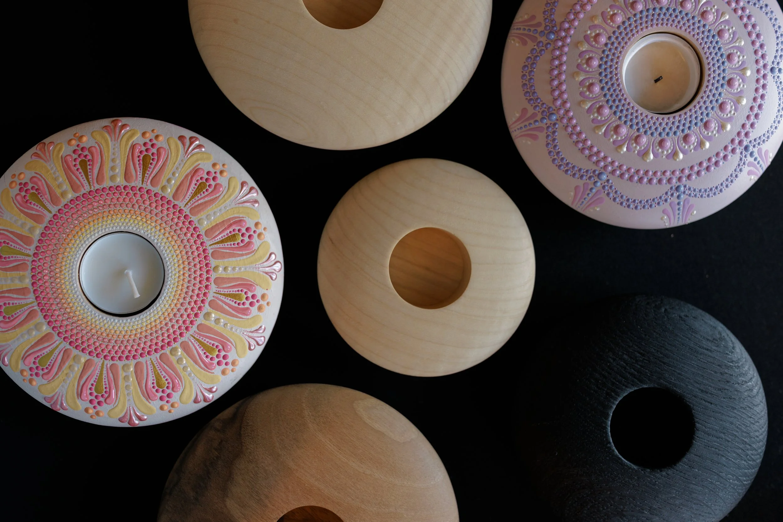 Decorative candles with intricate patterns and colors on a black background.