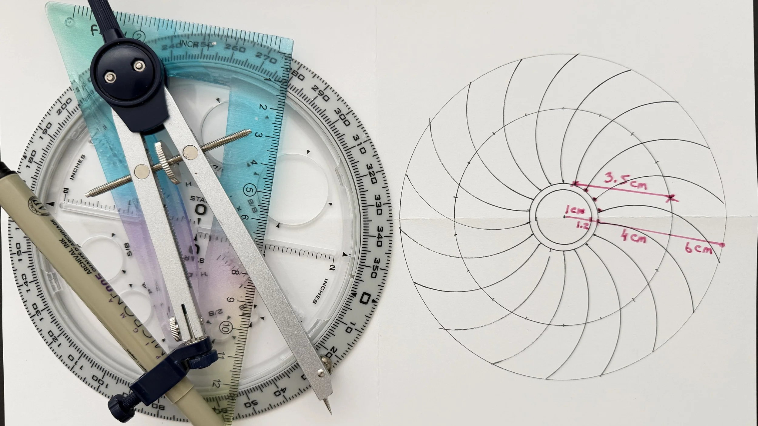 A laser distance measuring instrument, a protractor, and a compass are placed on a white surface. There is a sketch of concentric circles with measurements written in pink marker.