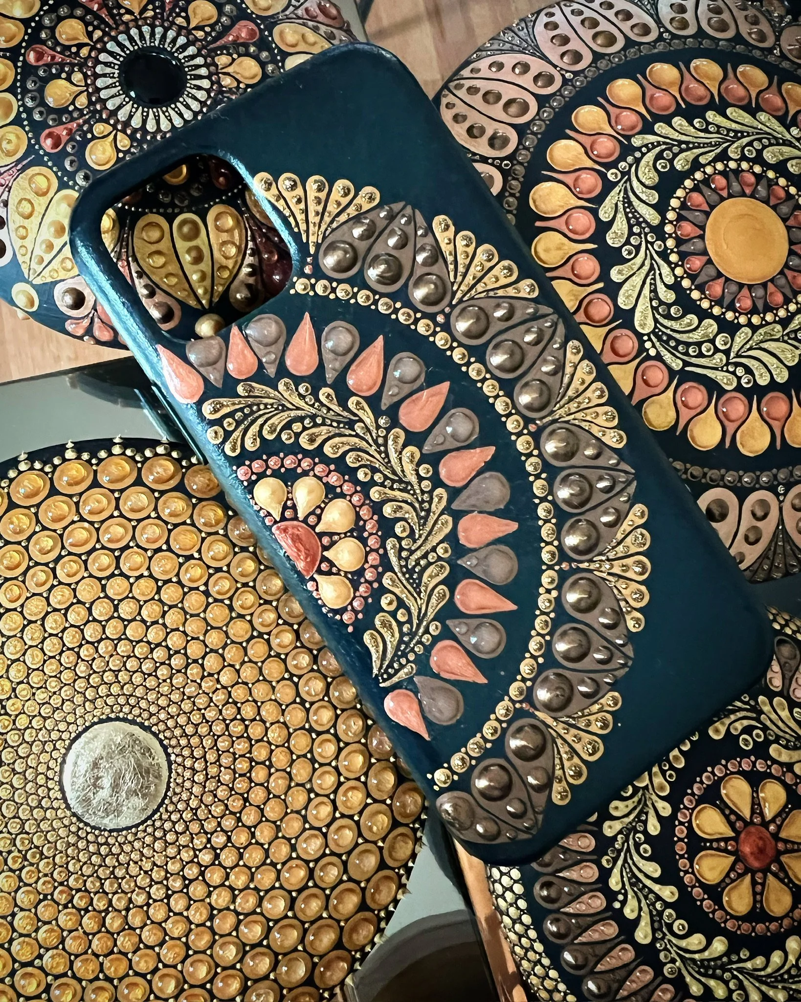 Decorative pottery with intricate patterns, dots, and leaf motifs in black, gold, copper, and silver colors.