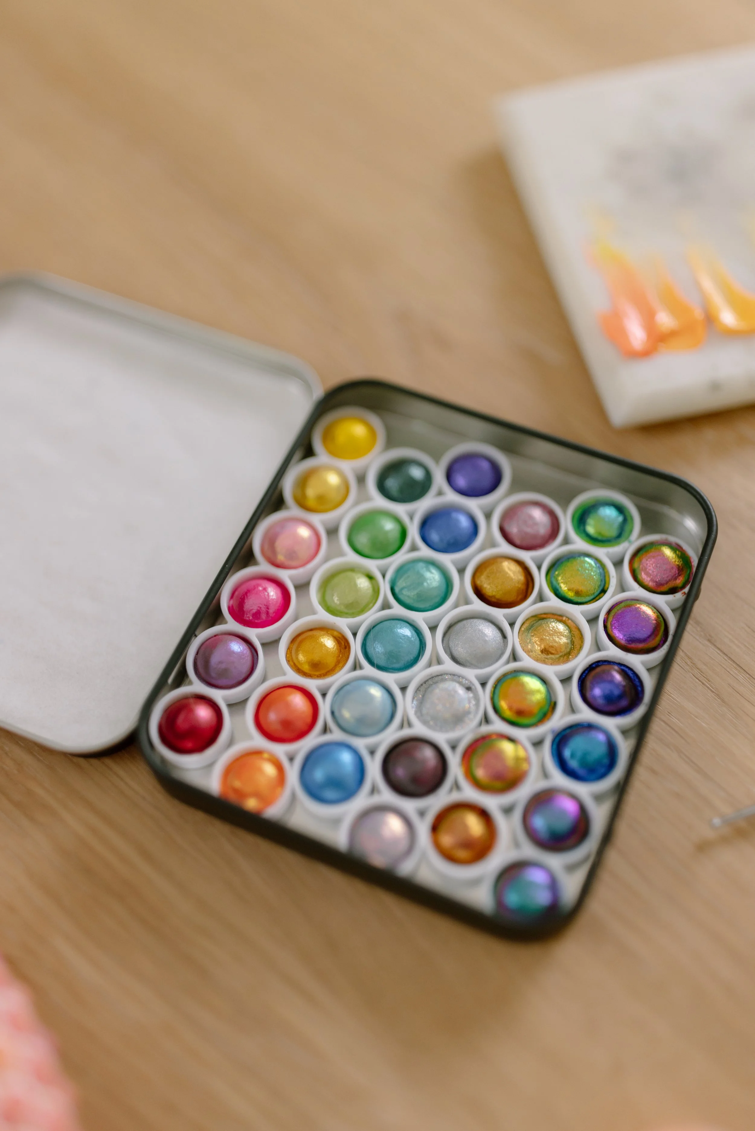 Close-up view of a metal container filled with colorful shiny items, with a partly visible blurred package on the side.