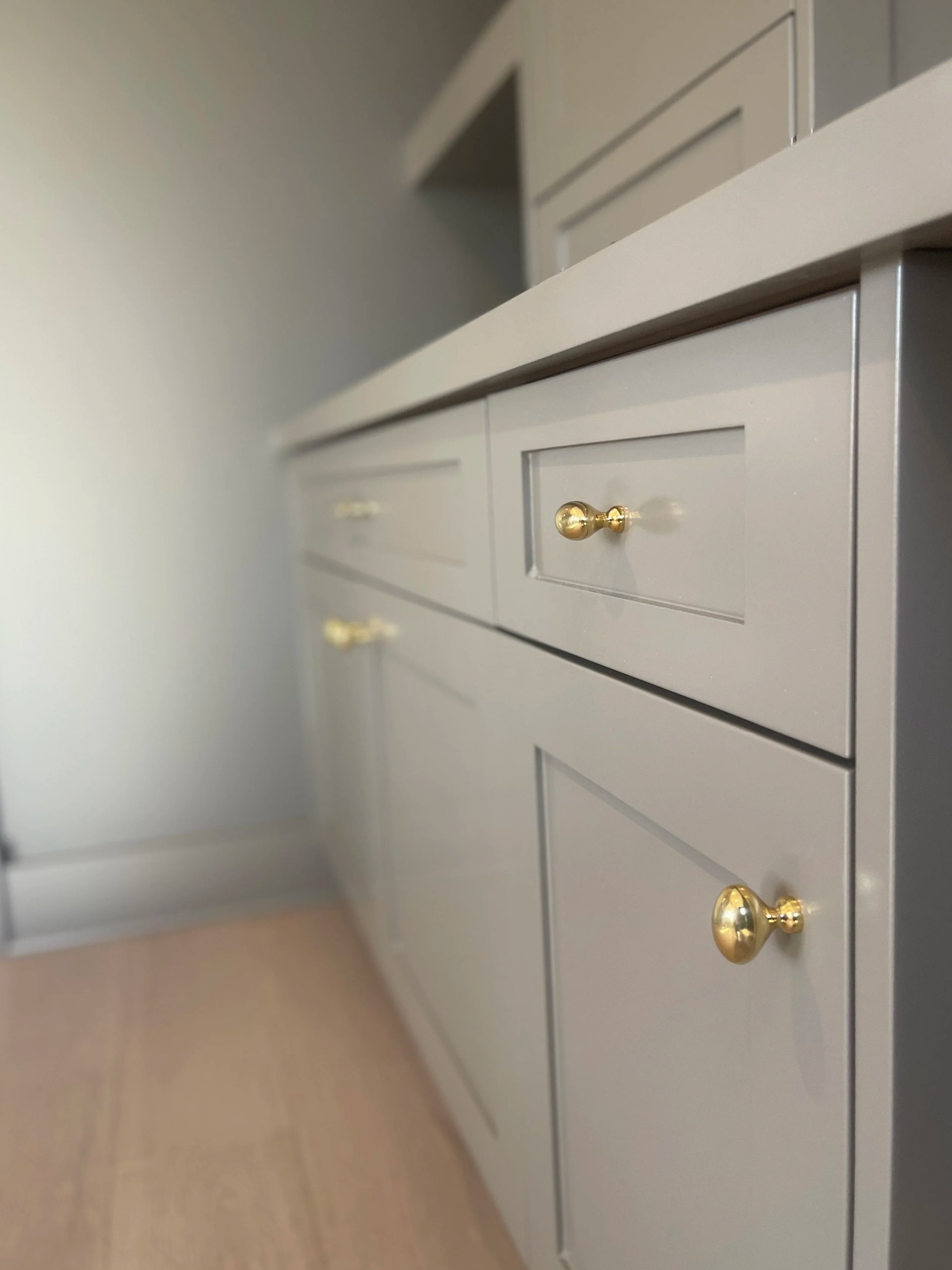 Custom Office and Window Sitting Area with under bench storage.  Color saturated with a moody gray paint with unlacquered brass knobs and pulls.