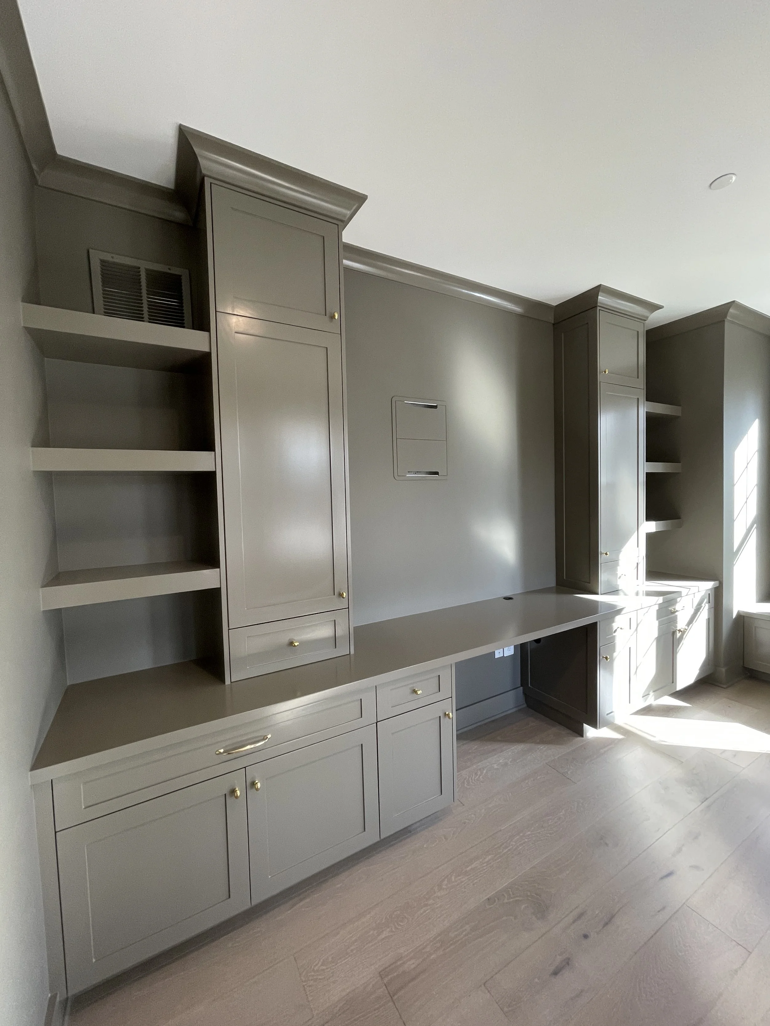 Custom Office and Window Sitting Area with under bench storage.  Color saturated with a moody gray paint with unlacquered brass knobs and pulls.