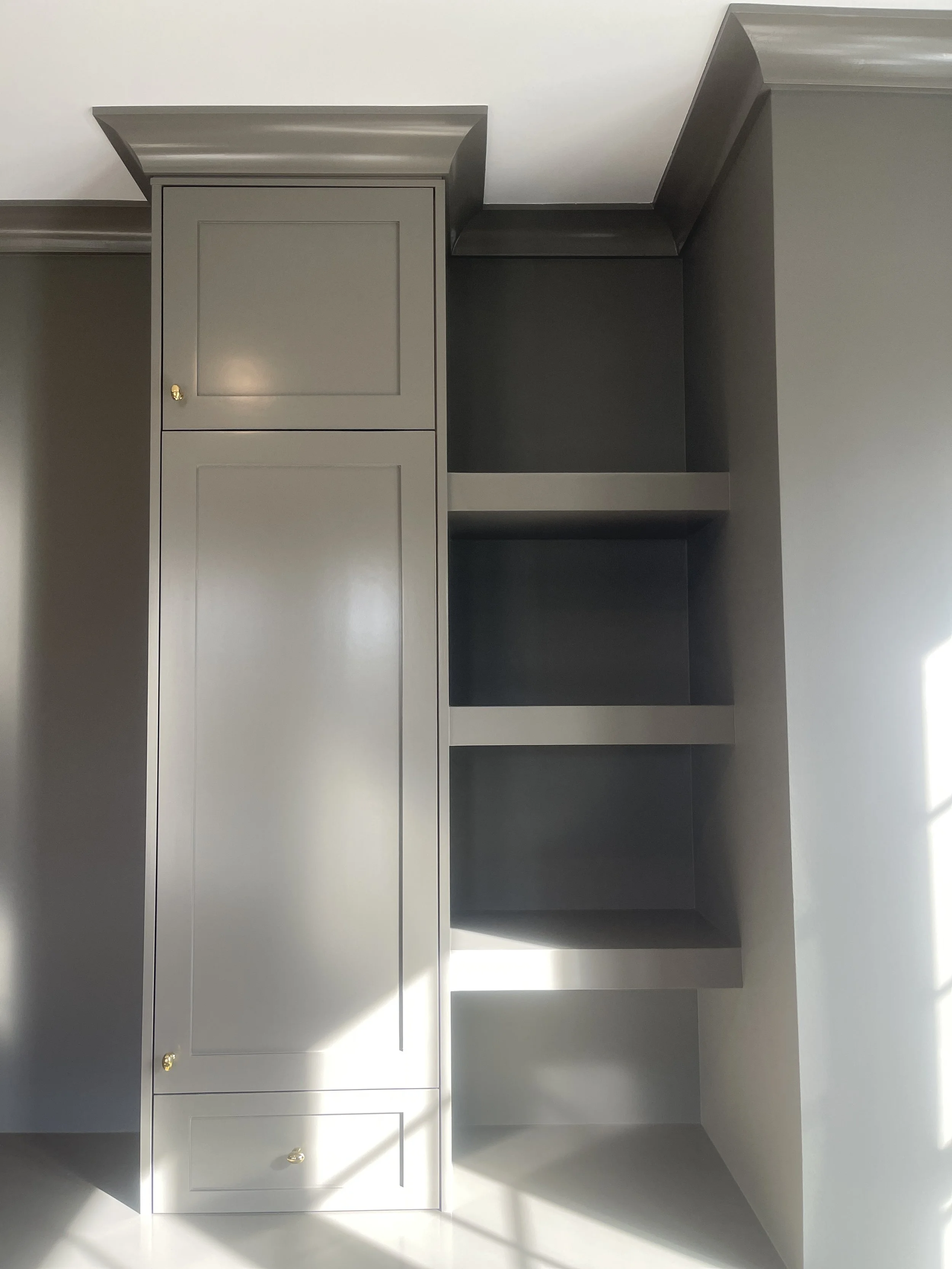 Custom Office and Window Sitting Area with under bench storage.  Color saturated with a moody gray paint with unlacquered brass knobs and pulls.
