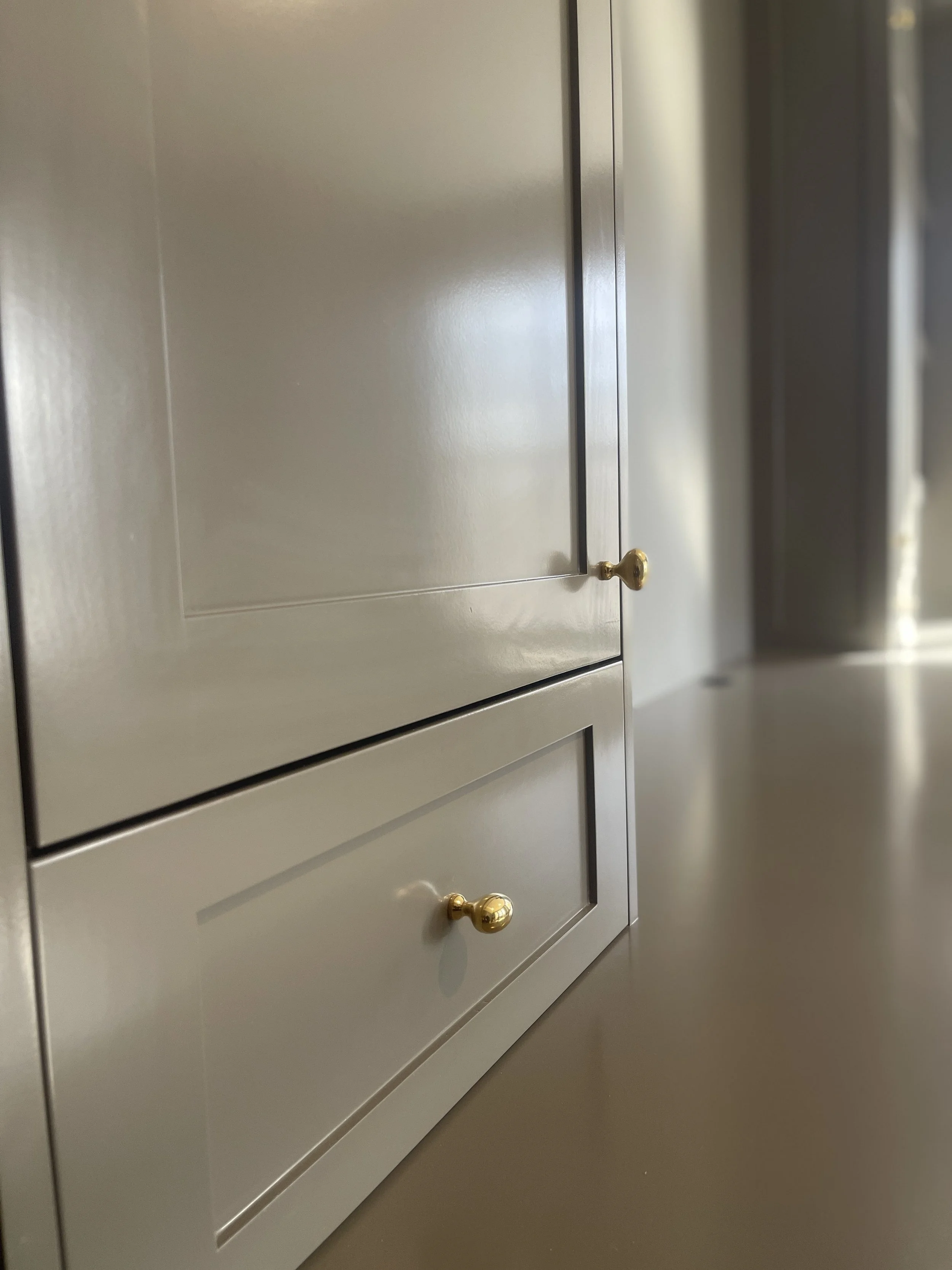 Custom Office and Window Sitting Area with under bench storage.  Color saturated with a moody gray paint with unlacquered brass knobs and pulls.