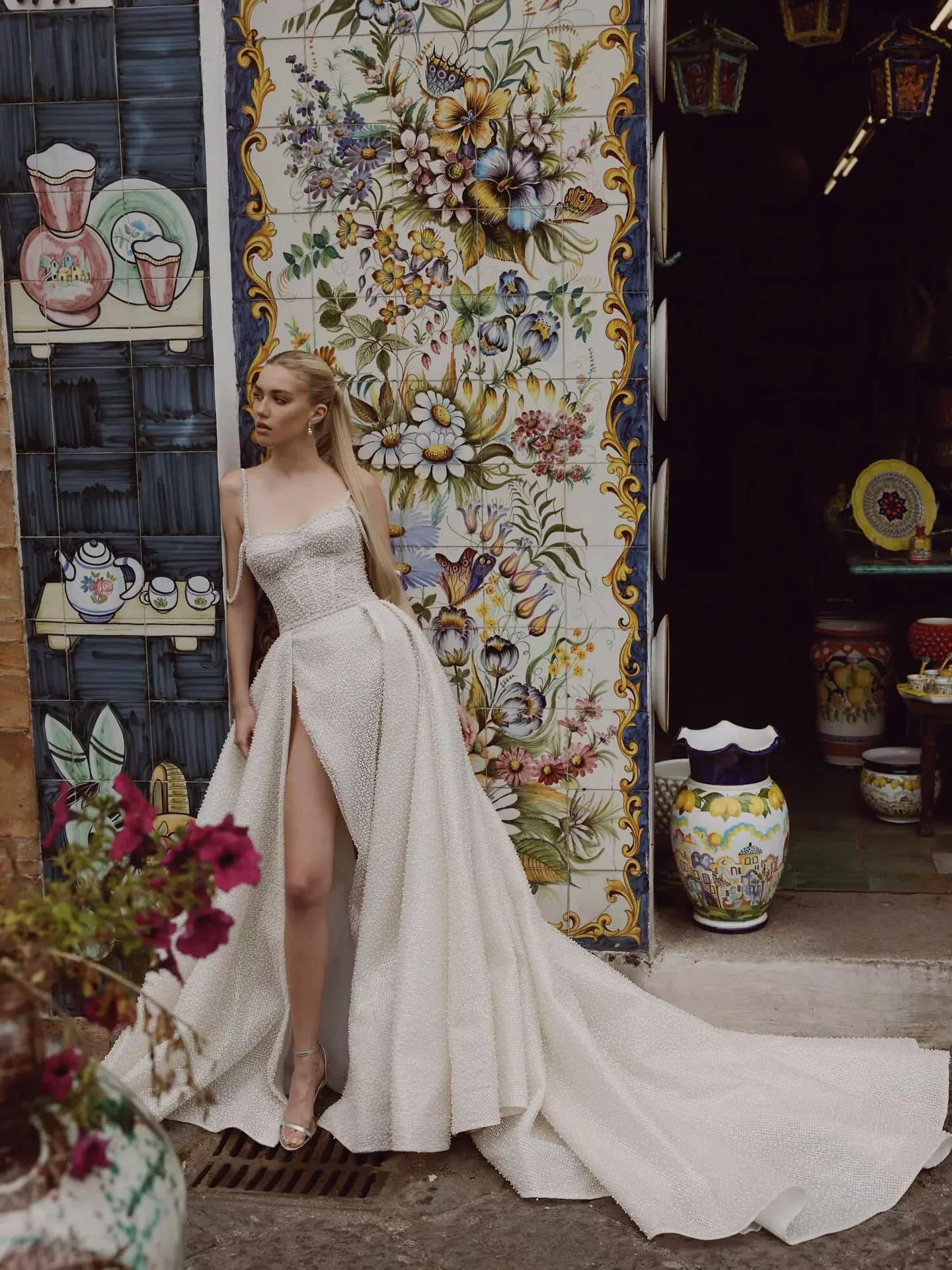 The Piera by Ricca Sposa. This mesmerizing wedding gown is a true embodiment of grace and glamour. Crafted from exquisite shimmering mesh with pearls. It boasts a deep slit on the leg and removable straps