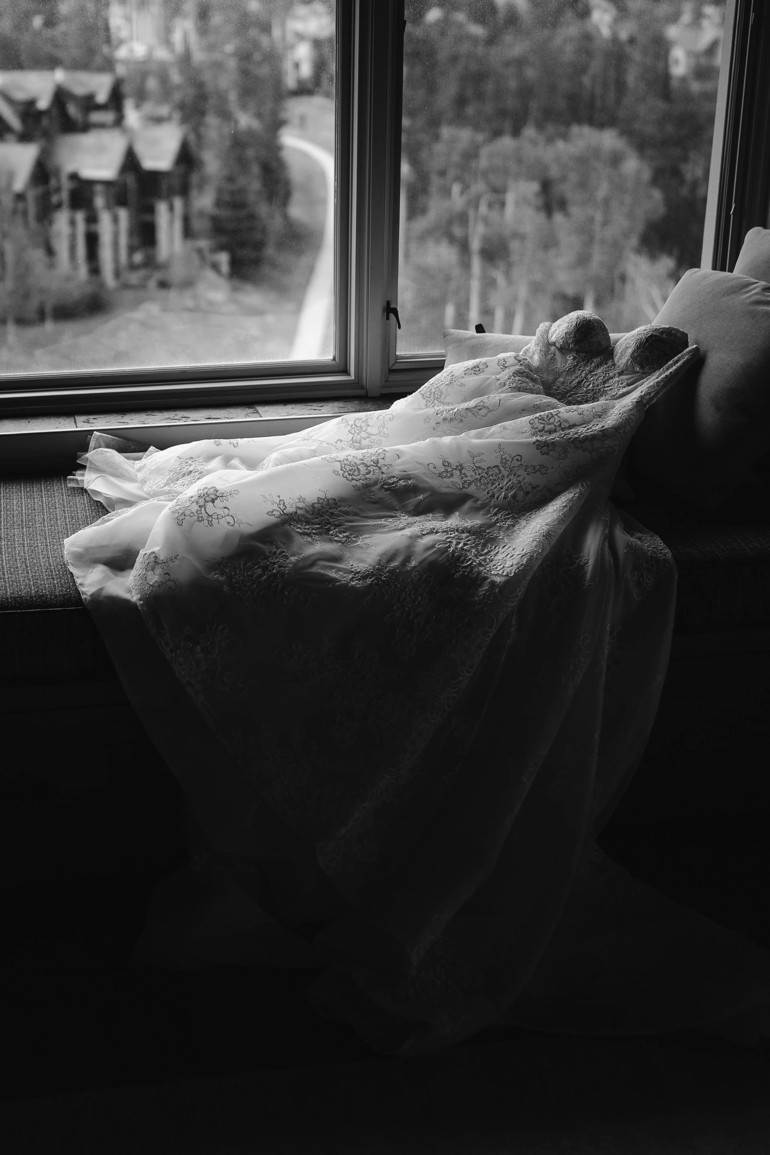 wedding dress draped over the couch in front of the hotel room window