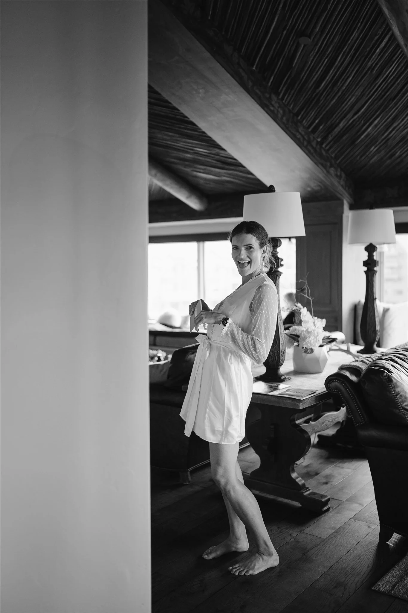 bride excitingly smiles at the camera in her robe