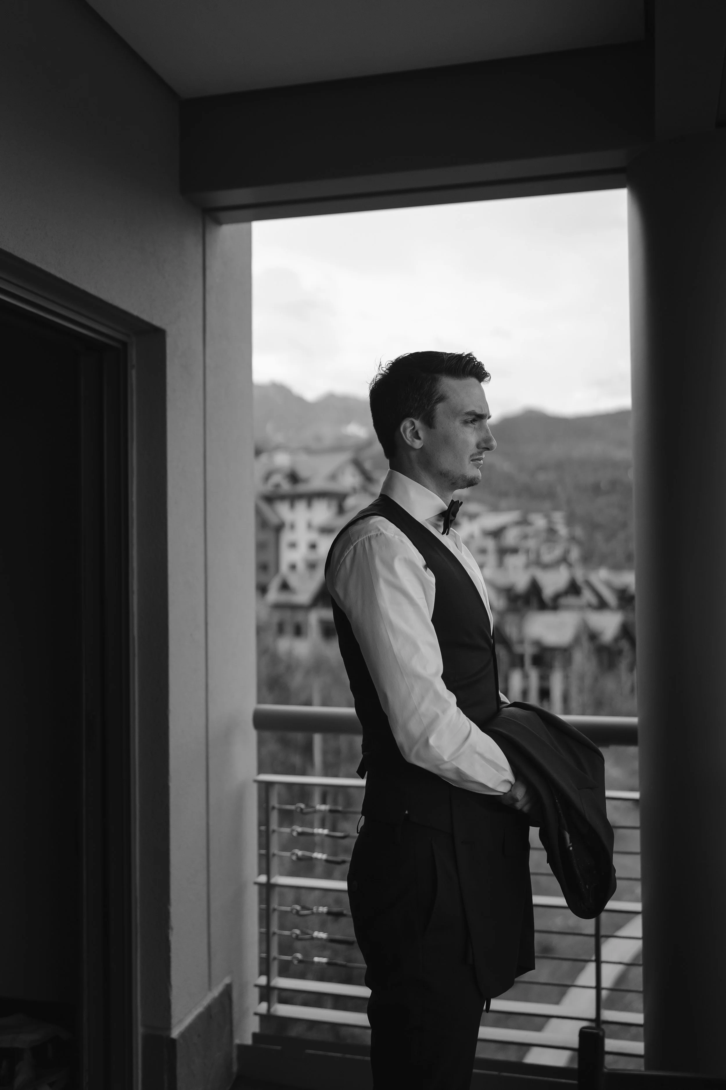groom admiring the mountain views from the hotel balcony