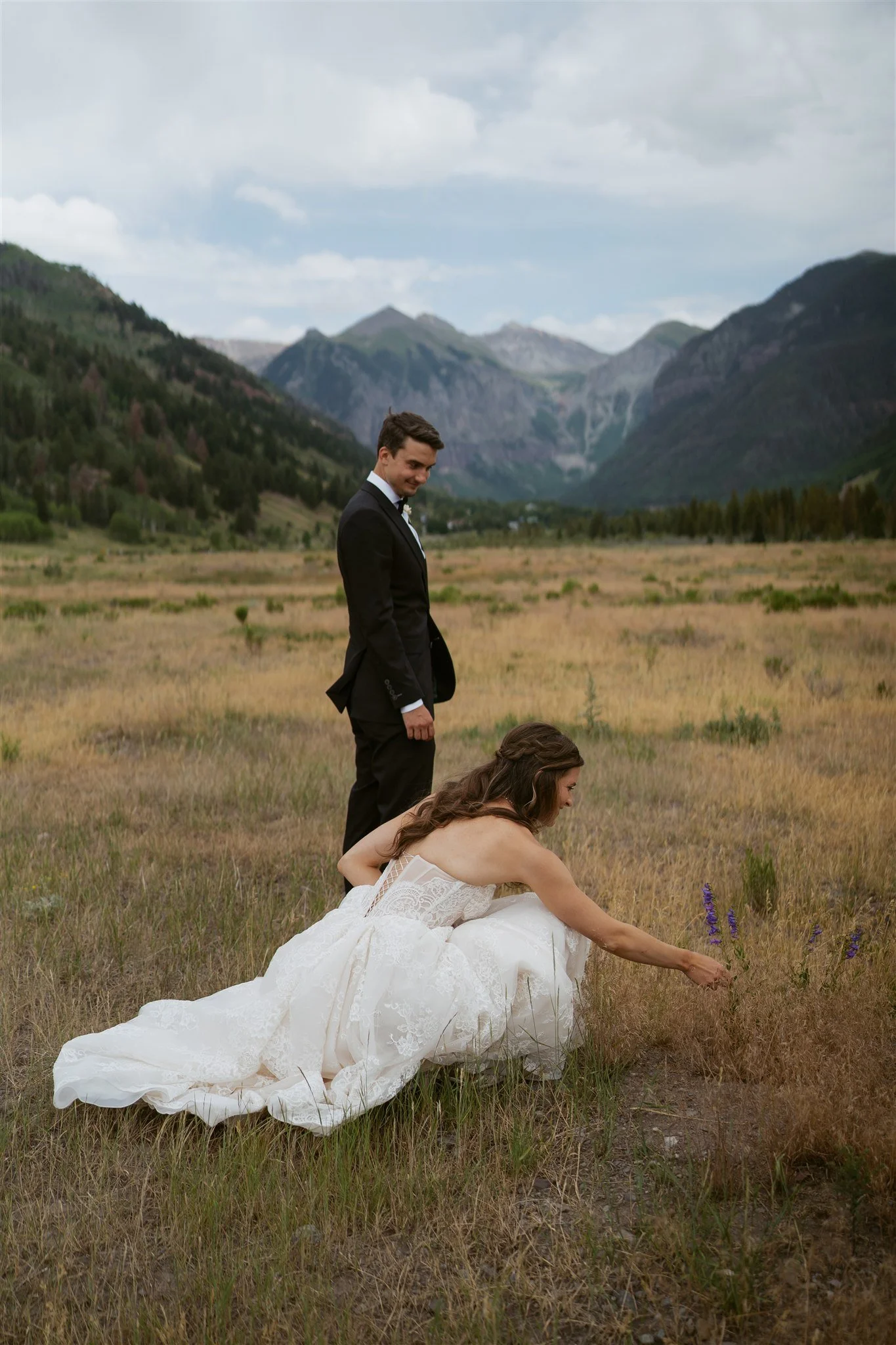groom watching the bride admire the flowers in the valley