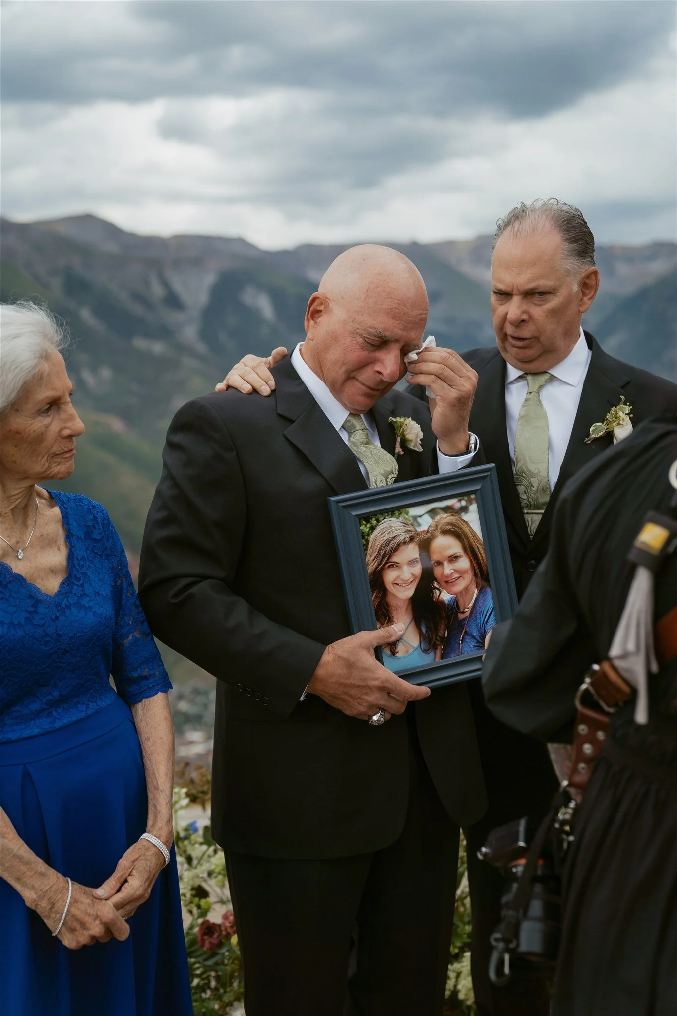 bride's father sheds a tear while holding a photo of the bride's late mother