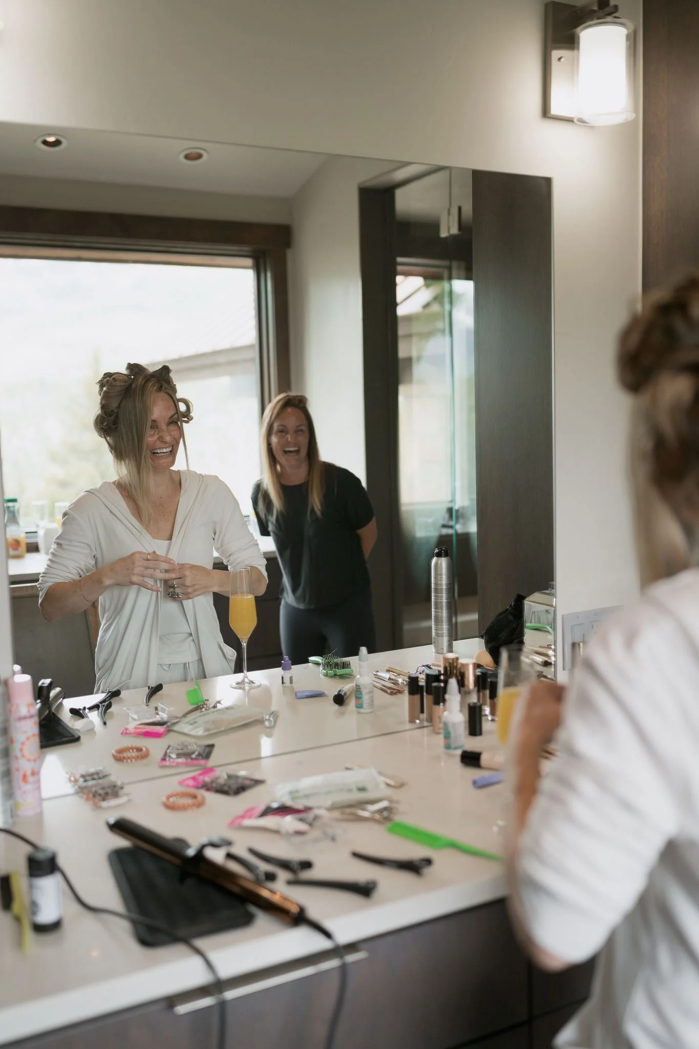 bride laughing with her sister in the mirror