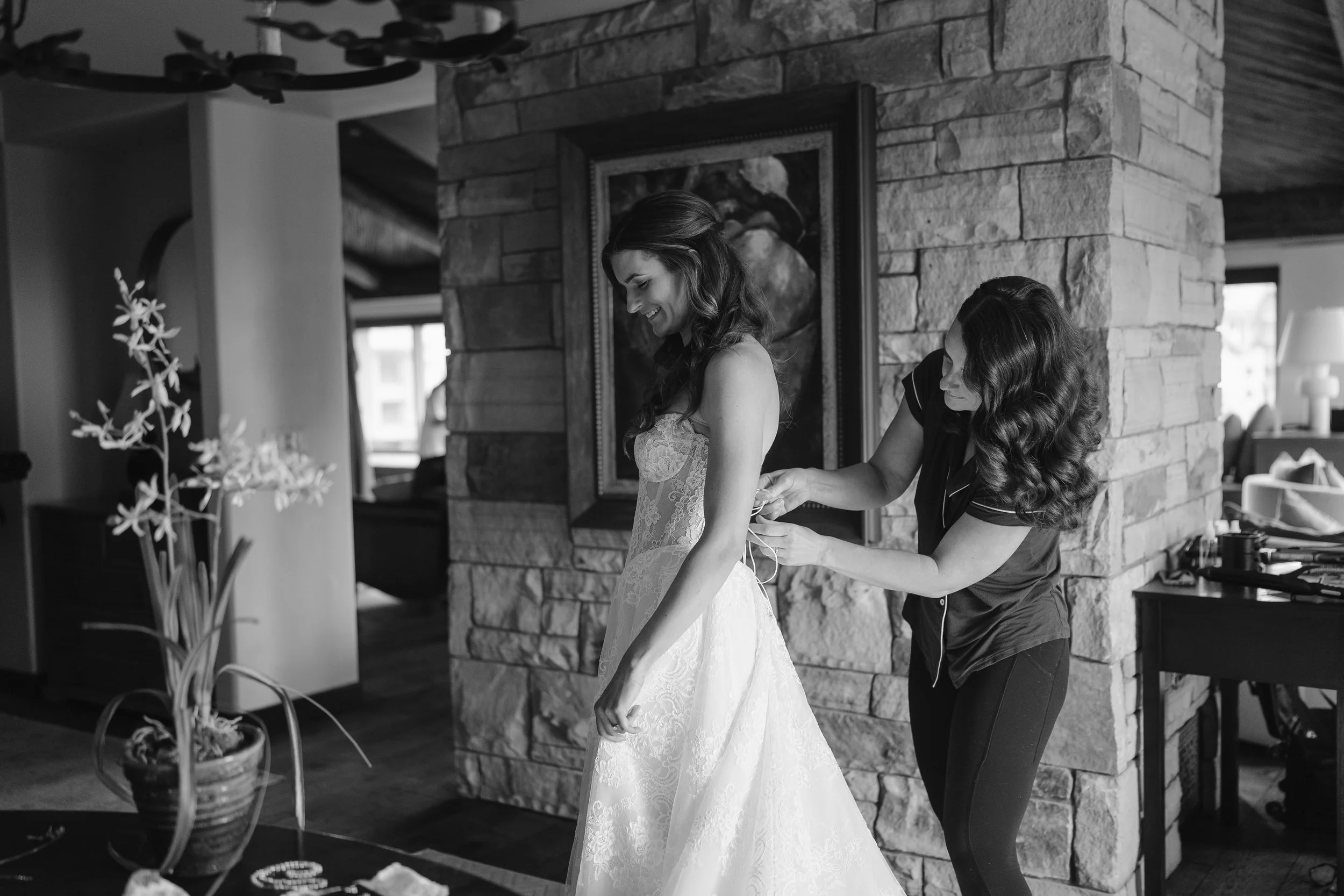 bride has help tying up her dress