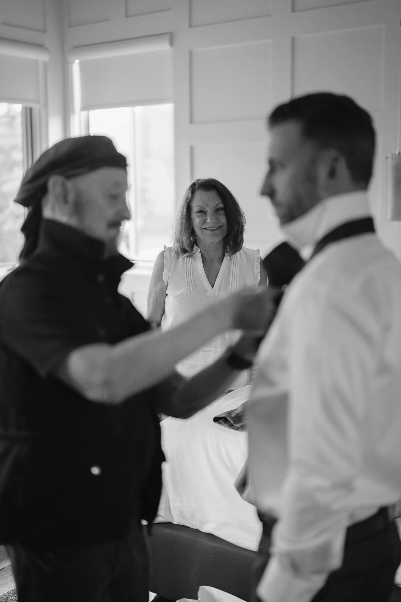 mom watches as dad helps son with tie
