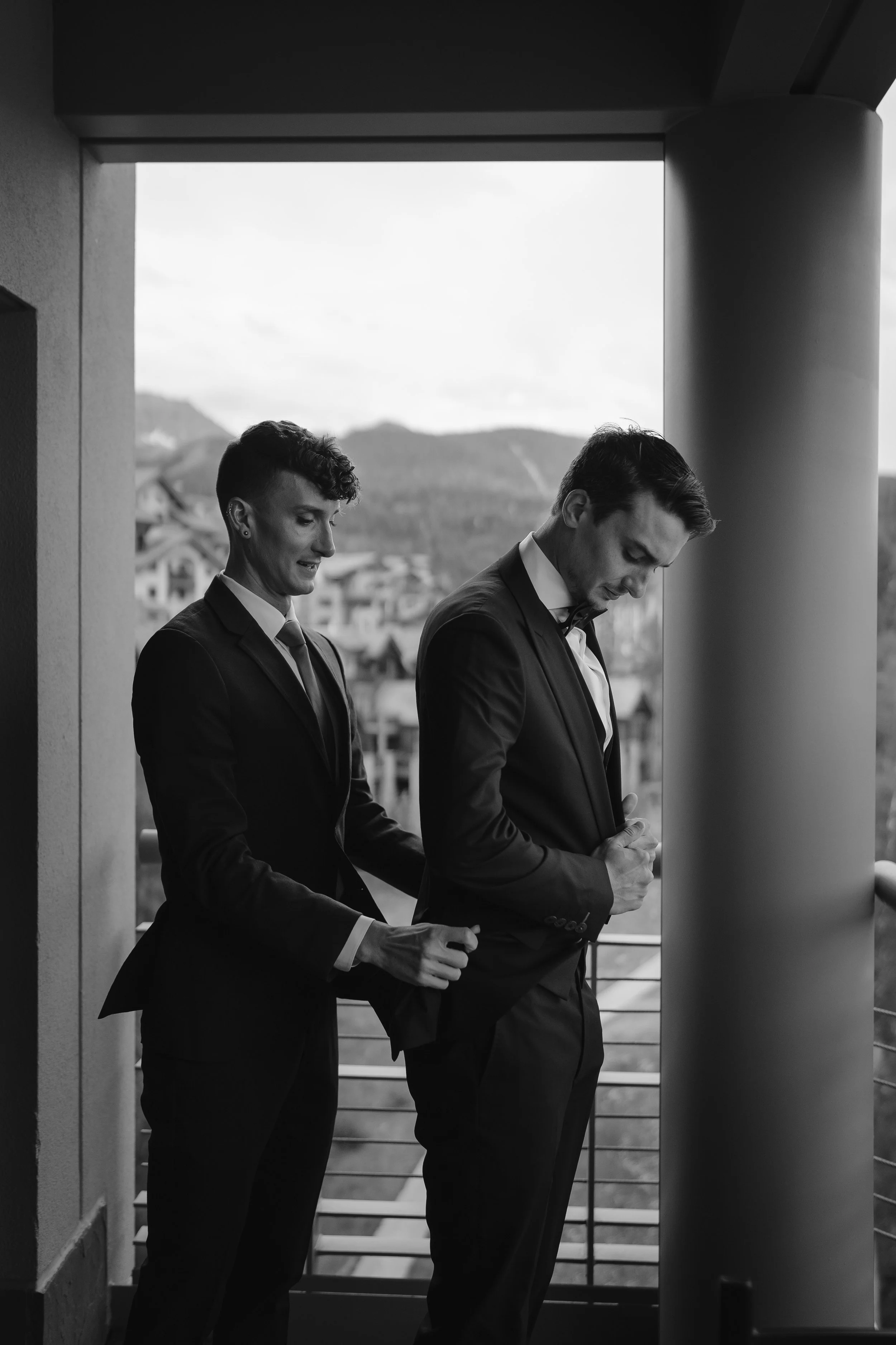 groom adjust his jacket while his brother lends a hand