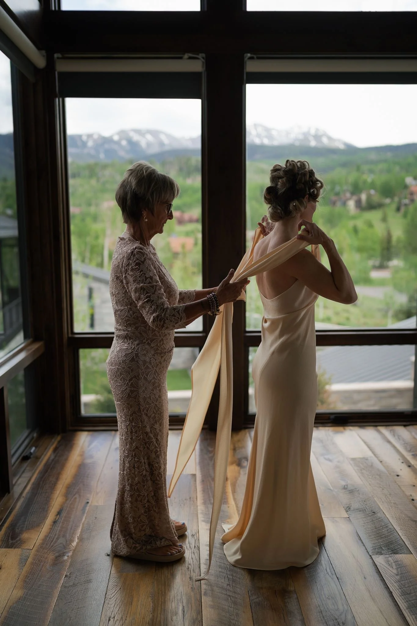 mom helps the bride put on her dress