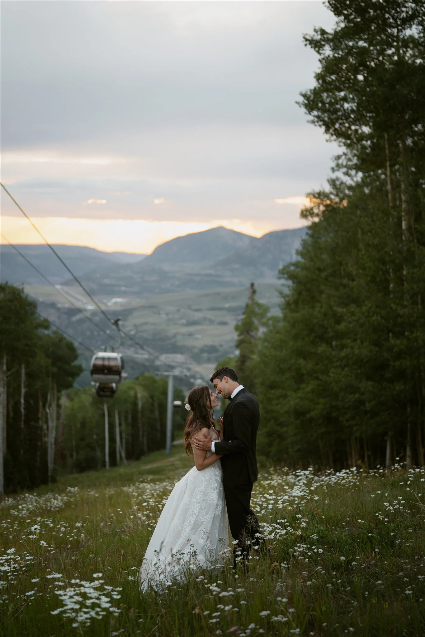 bride and groom in a flower field with the Telluride gondola in the background