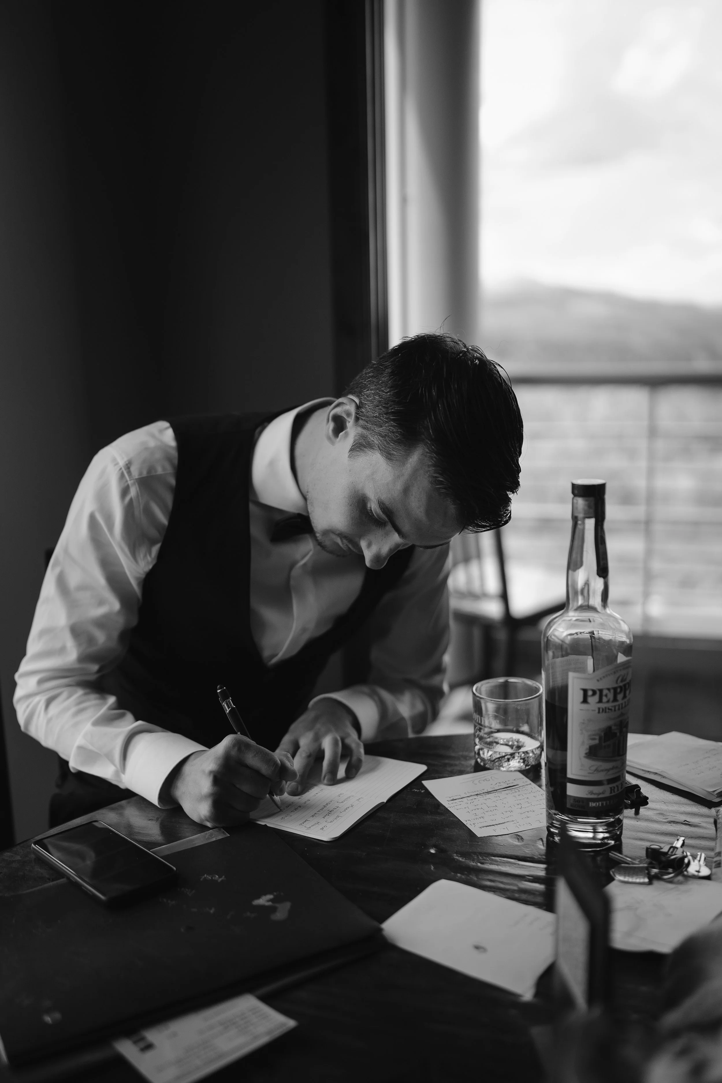 groom writing his vows at the table in his hotel room