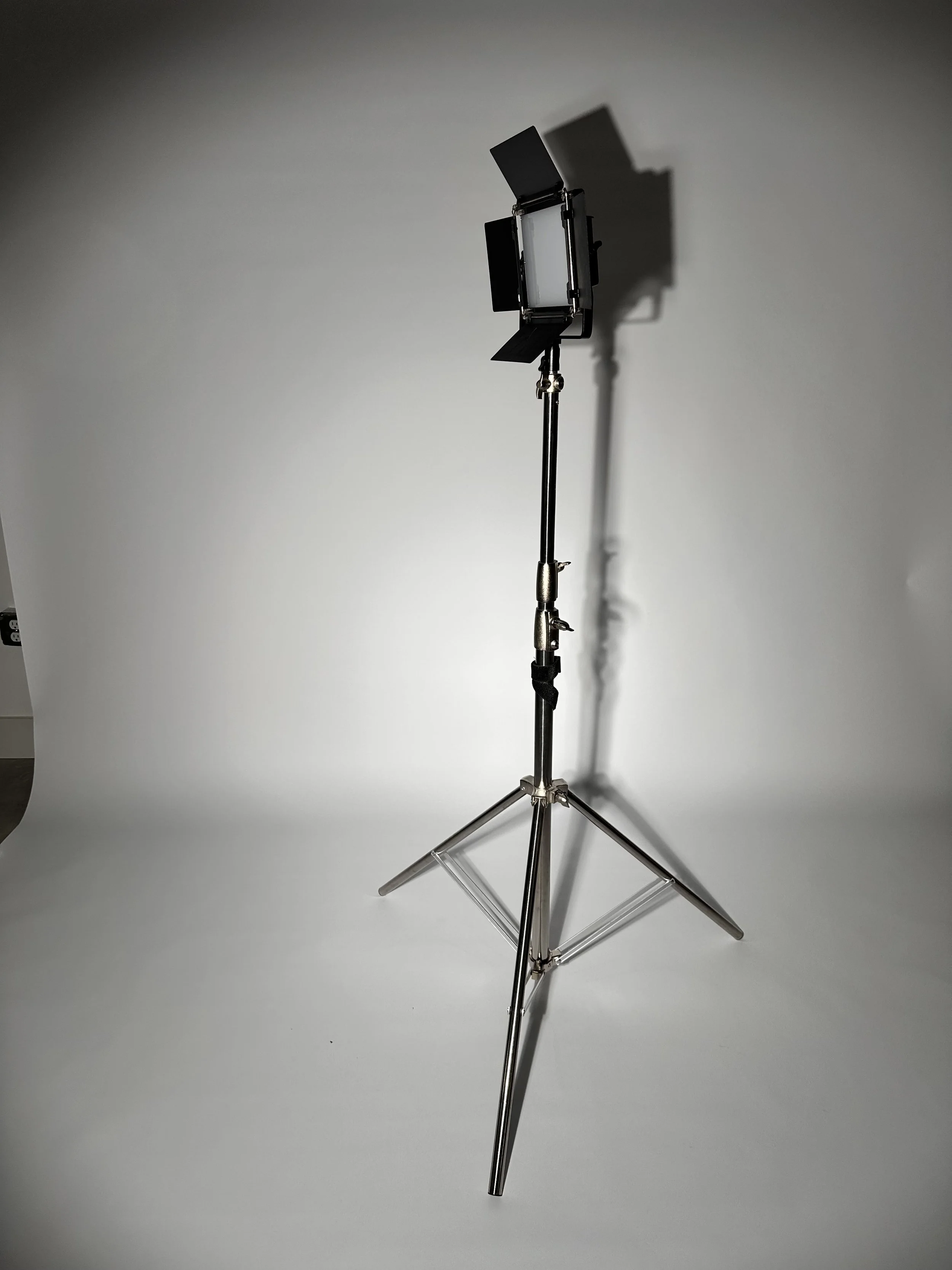Photography studio lighting equipment on a stand with a white backdrop.