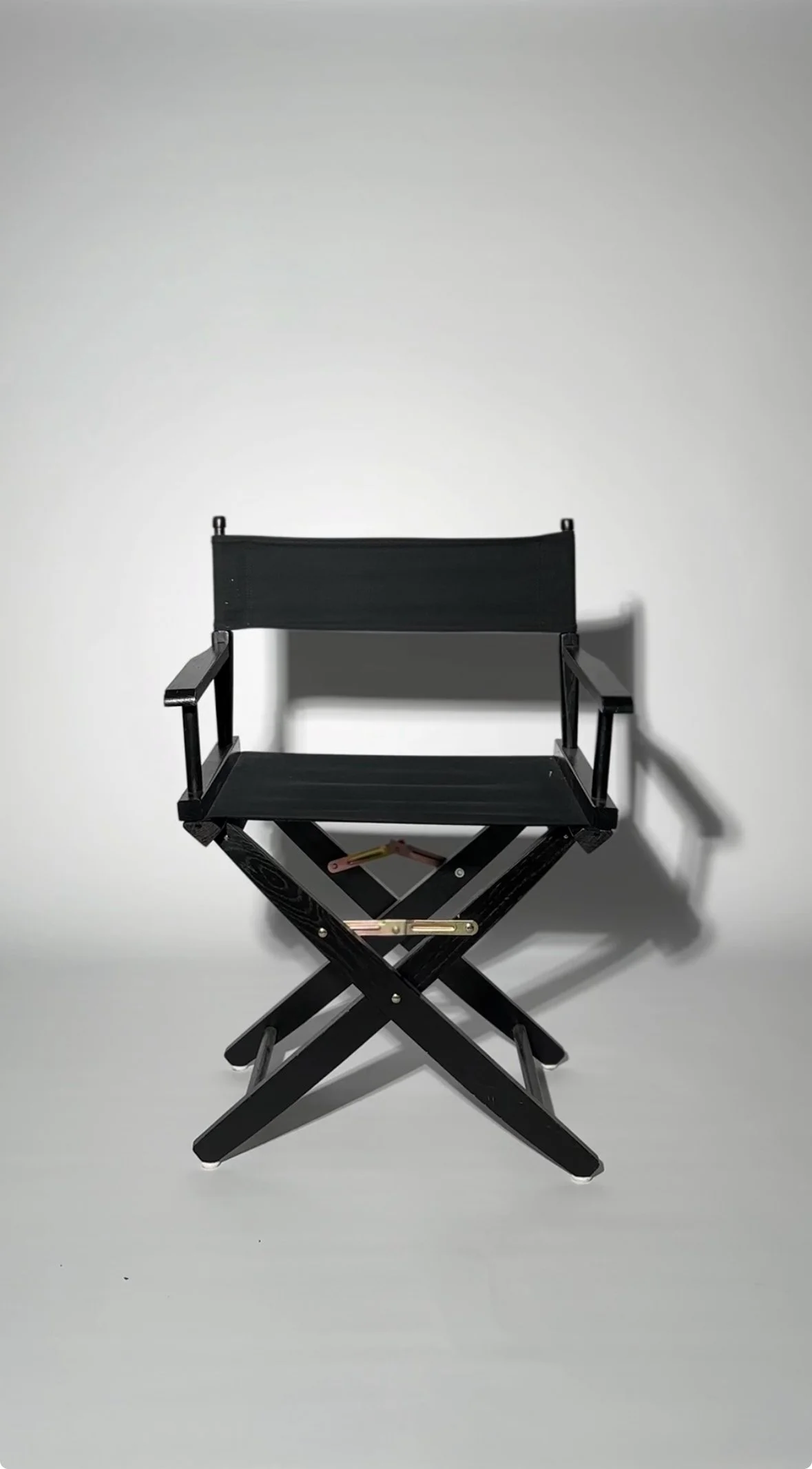A black director's chair with a foldable wooden frame positioned against a plain white background at a photography studio in San Antonio, Texas.