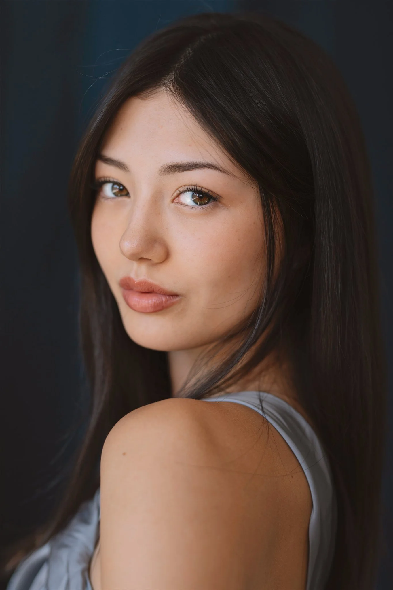 Miku Martineau actor headshot, soft expression with blue backdrop