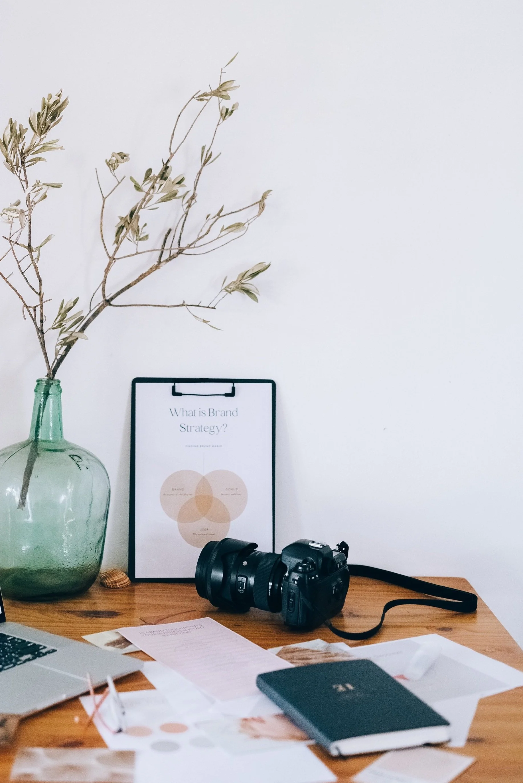 Brown leather zippered pouch with a notebook inside, featuring a decorative zipper pull shaped like a vintage telephone.