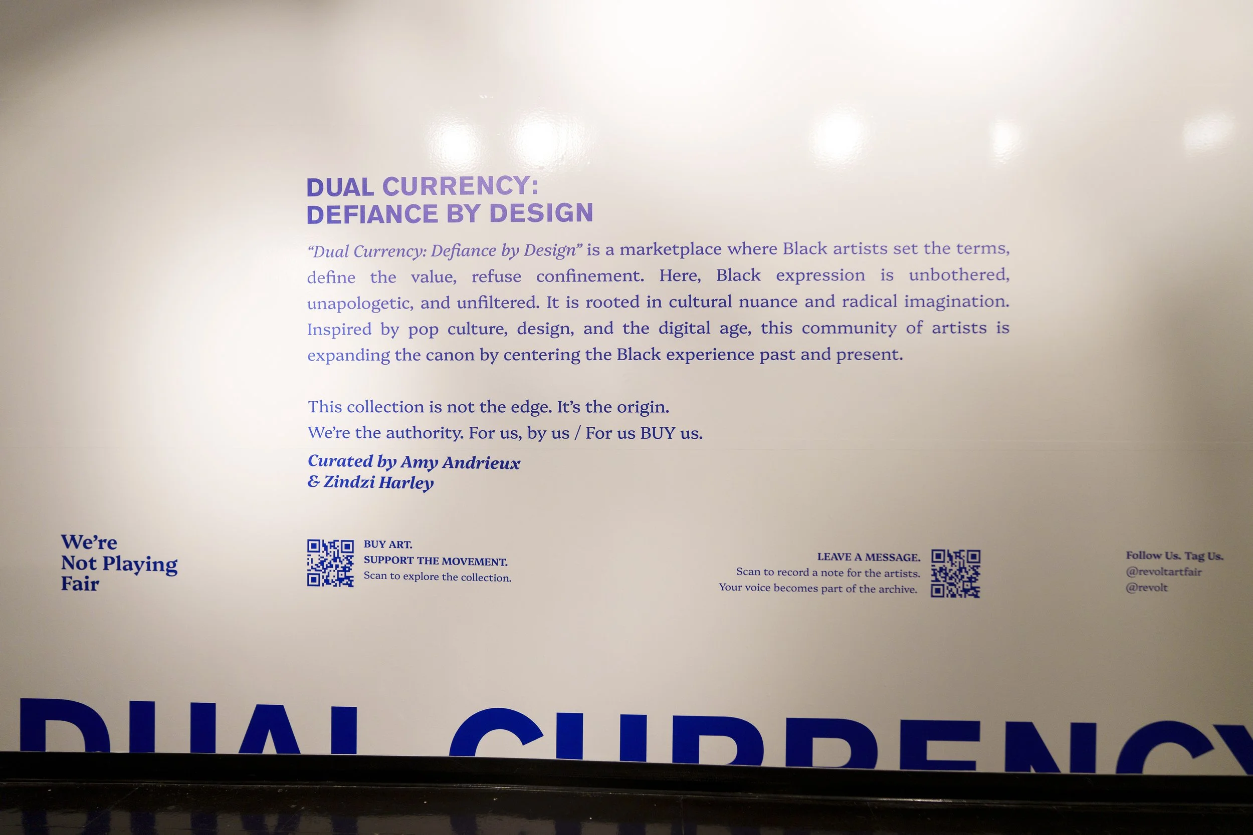 Sign with information about the 'Dual Currency: Defiance by Design' art collection, including a description, curators, and QR codes for exploring the collection and recording notes.