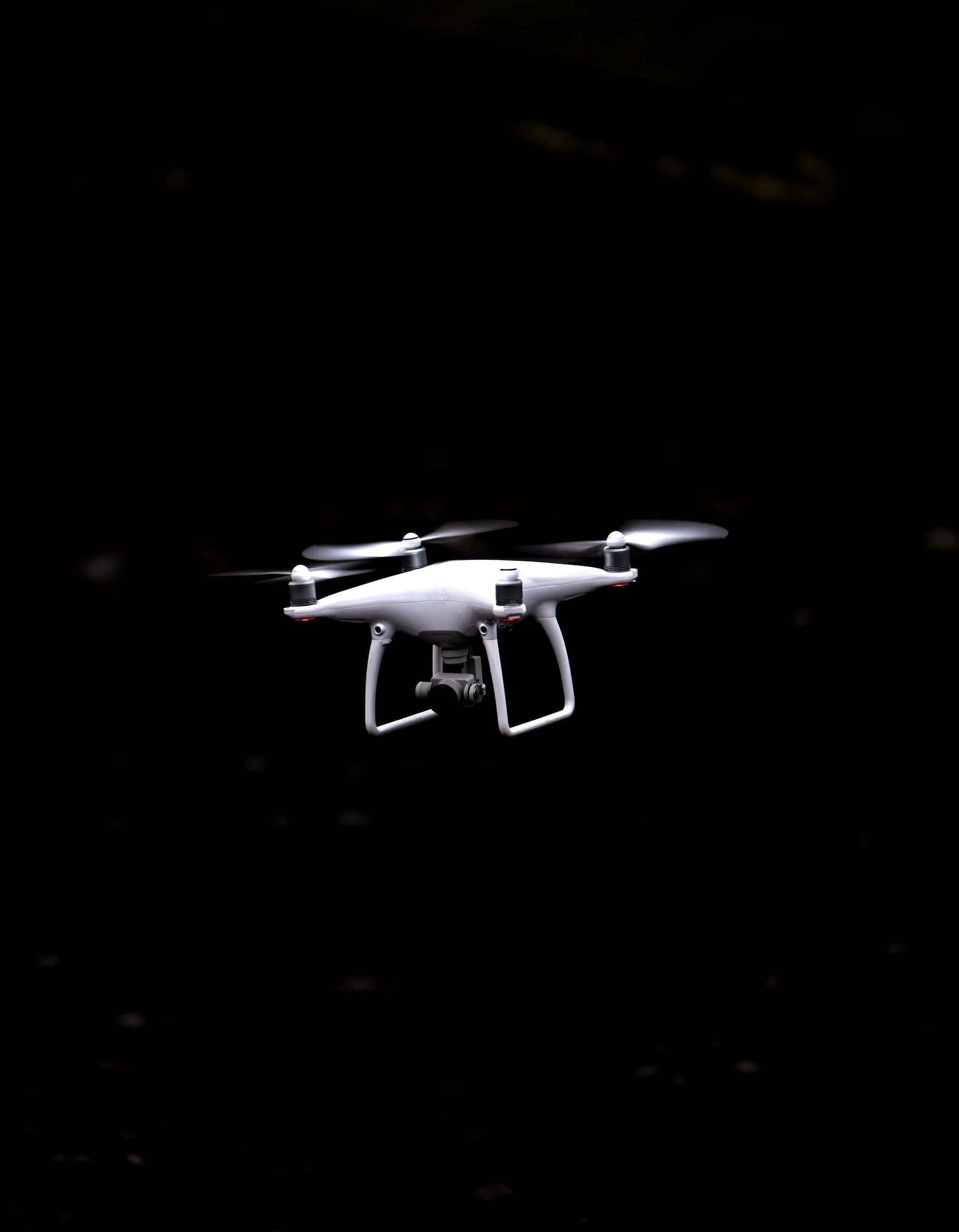 White drone flying against a dark background