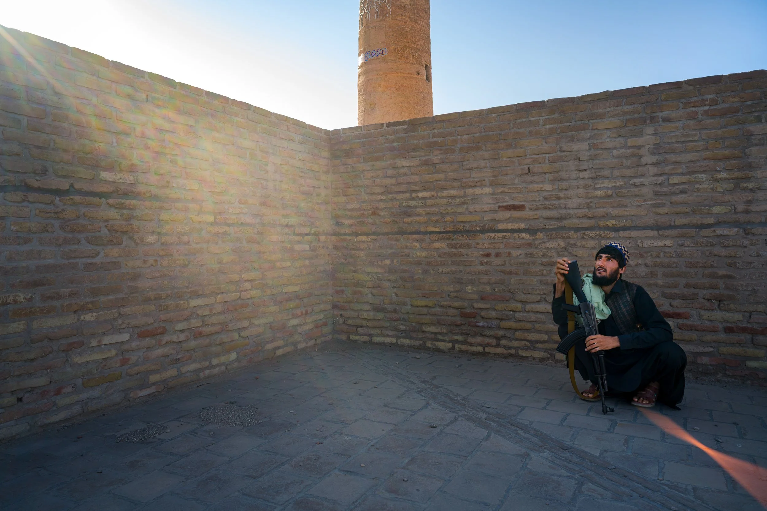A Taliban guard shelters from the sun within the walls surrounding the city's ancient minarets.
 His role is to protect the site from abuse and vandalism, safeguarding a legacy of faith and memory for future generations, pending a major restoration.