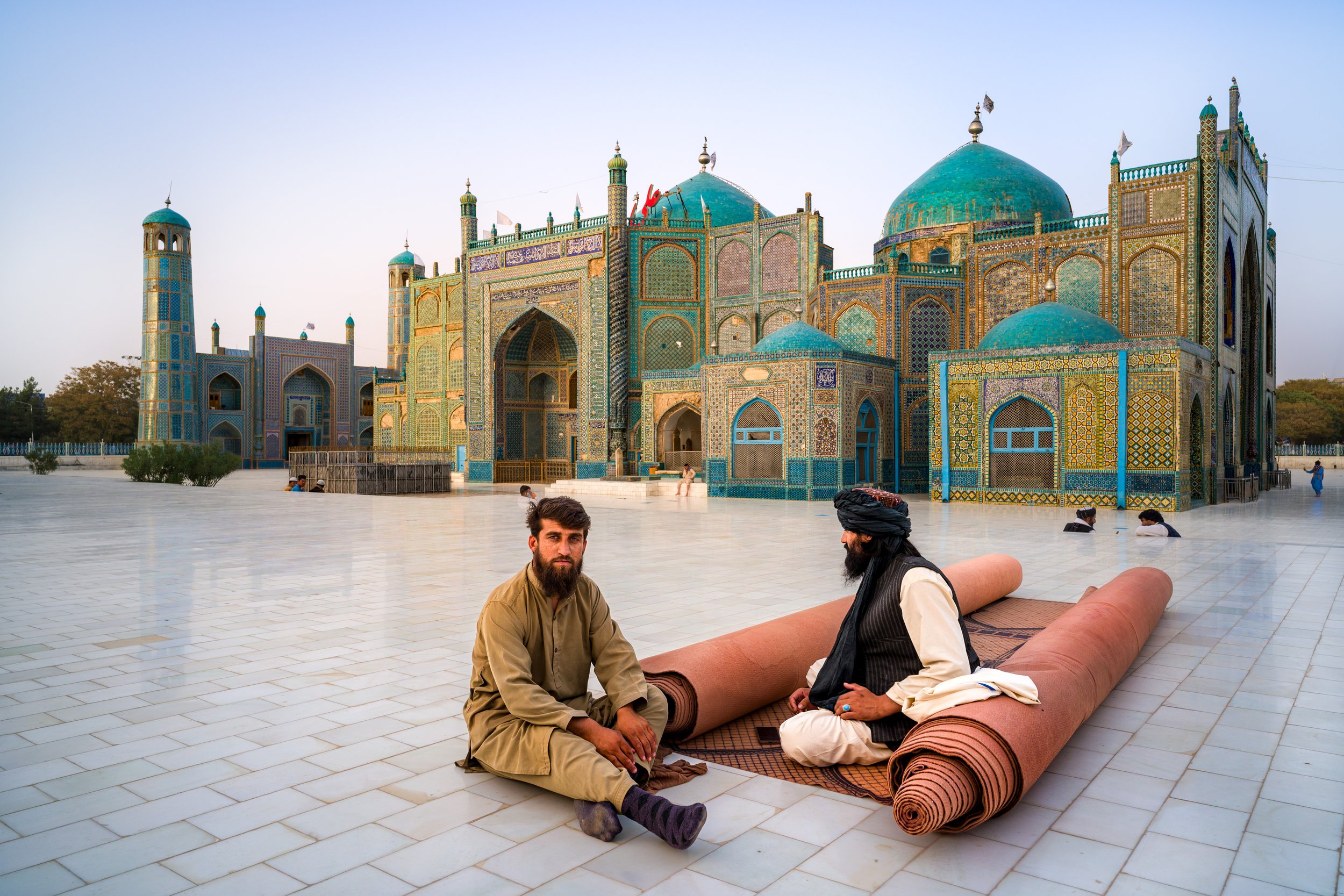 As sunset envelops the magnificent Blue Mosque of Mazar-i Sharif, a man pauses to converse with a local Taliban member, intent on praying on a rug. As I pass by them, our eyes meet, time slows, a nod of greeting begins, and a new but brief conversati