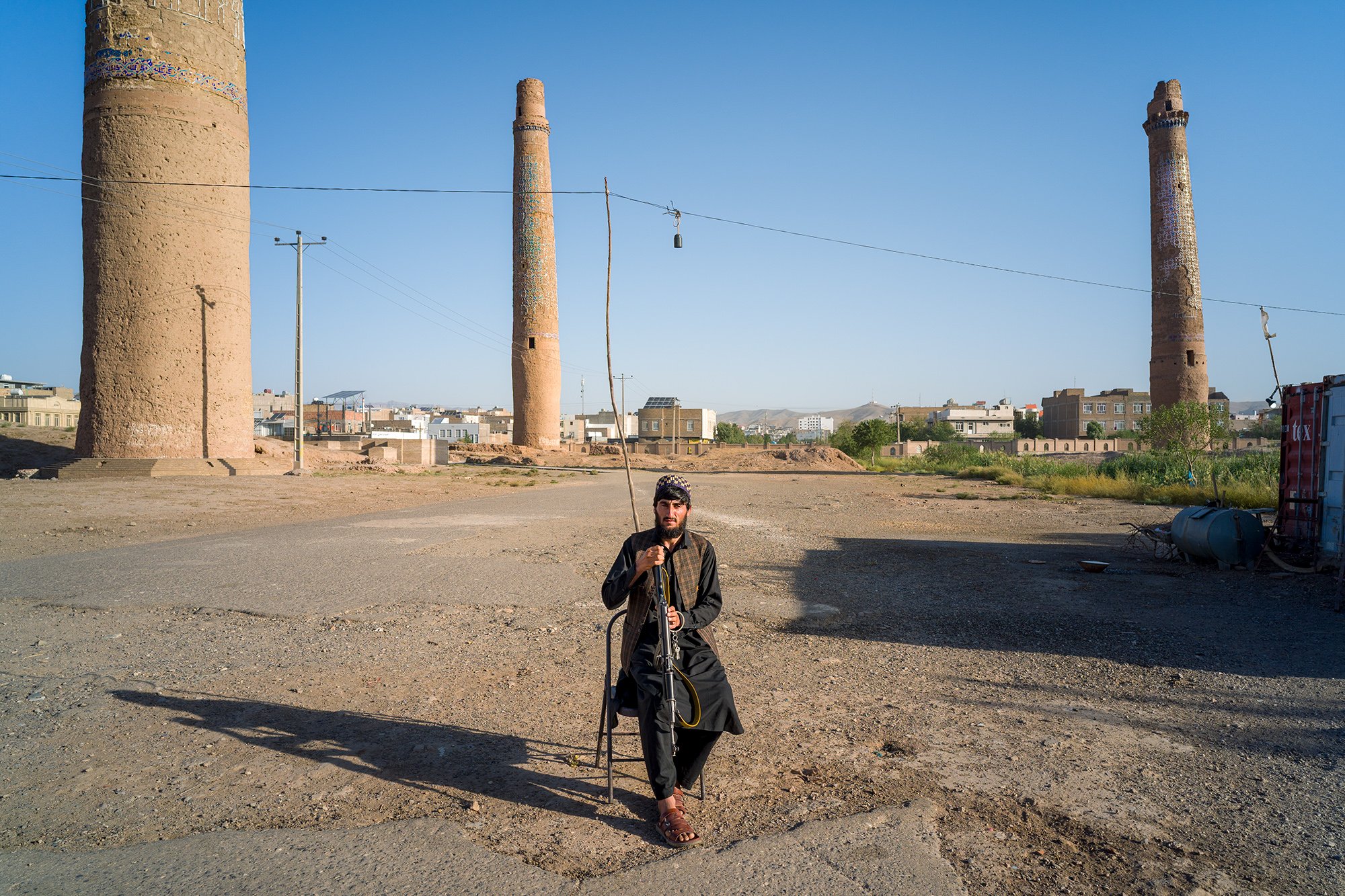 At the center of the fenced square that houses the ancient minarets of Herat, a young, armed Taliban man sits vigilantly in his chair, guardian of a now fragile historical and sacred treasure. His role is to protect the site from abuse and vandalism,