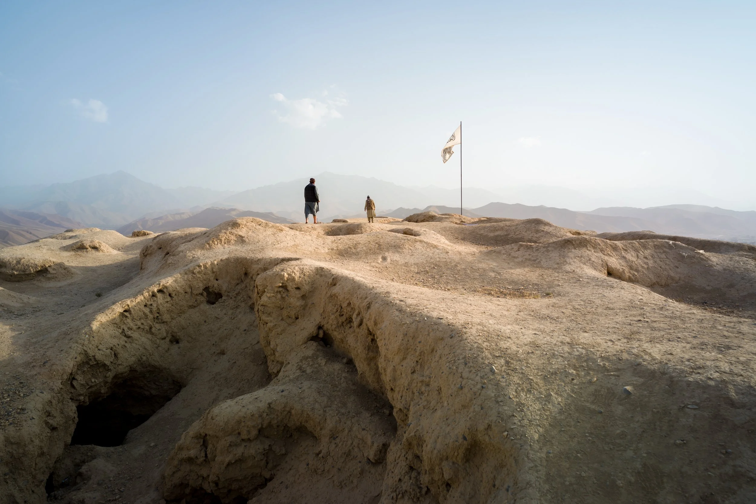 A Taliban flag flutters atop the ruins of Shahr-e Gholghola, where the now-replaced Afghan tricolor once stood. This flag, present in every prominent place in the country, is a symbol of an authority that protects while dominating a land where faith,
