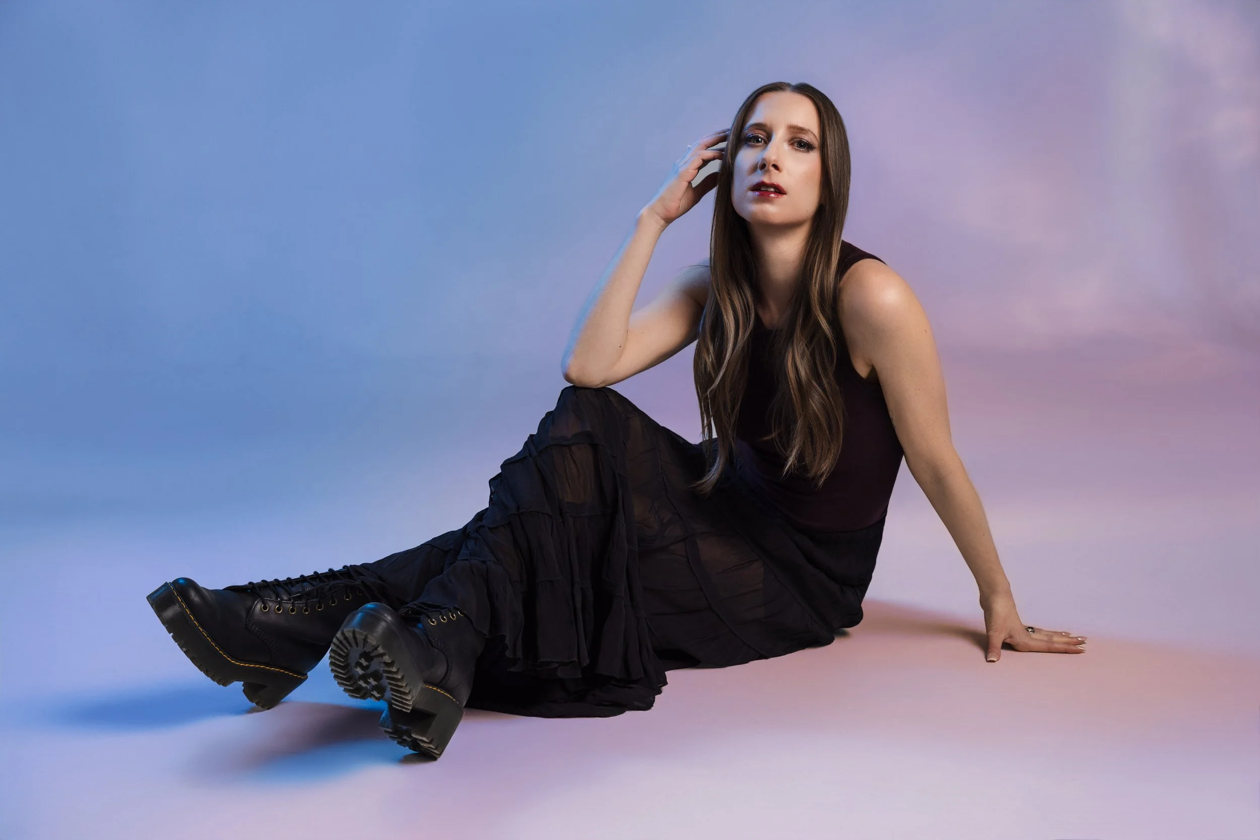 Artist portrait of Lauren River using gelled lights bounced off mylar to create colorful wall reflections in a dramatic studio lighting setup.