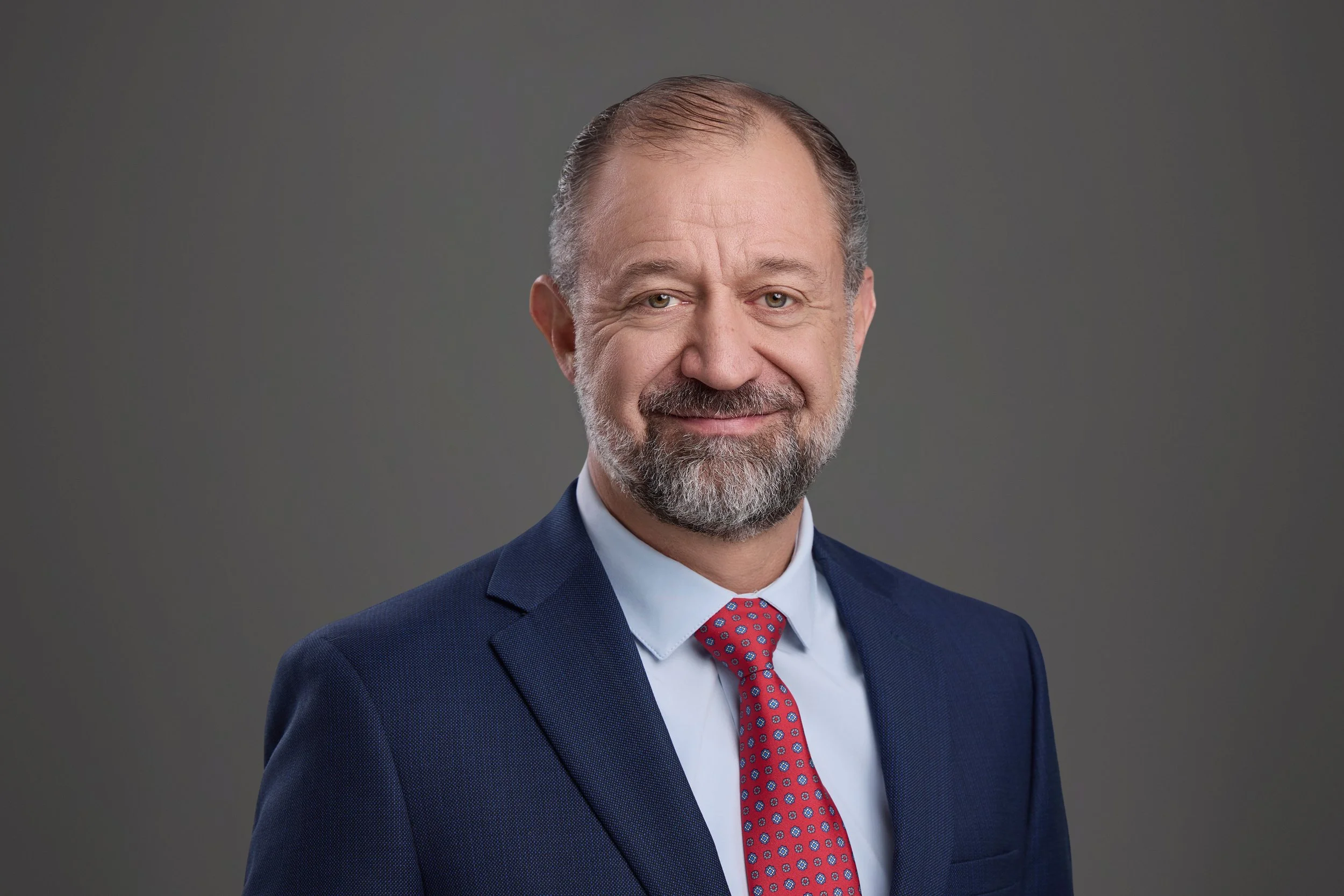 Executive headshot of a Thompson Burton leader in a navy suit and red patterned tie on a charcoal backdrop, photographed by Franklin TN headshot photographer Tausha Dickinson