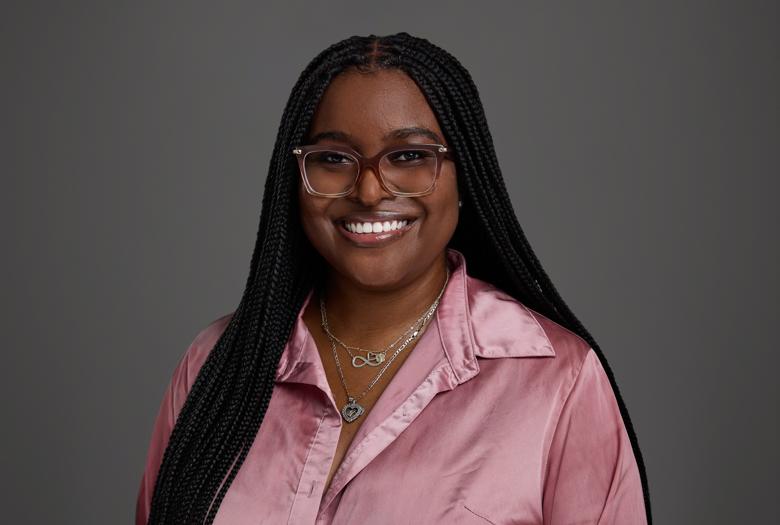 Professional headshot of a smiling Thompson Burton team member in glasses and a pink satin blouse, part of a cohesive law firm headshot session by Nashville photographer Tausha Dickinson