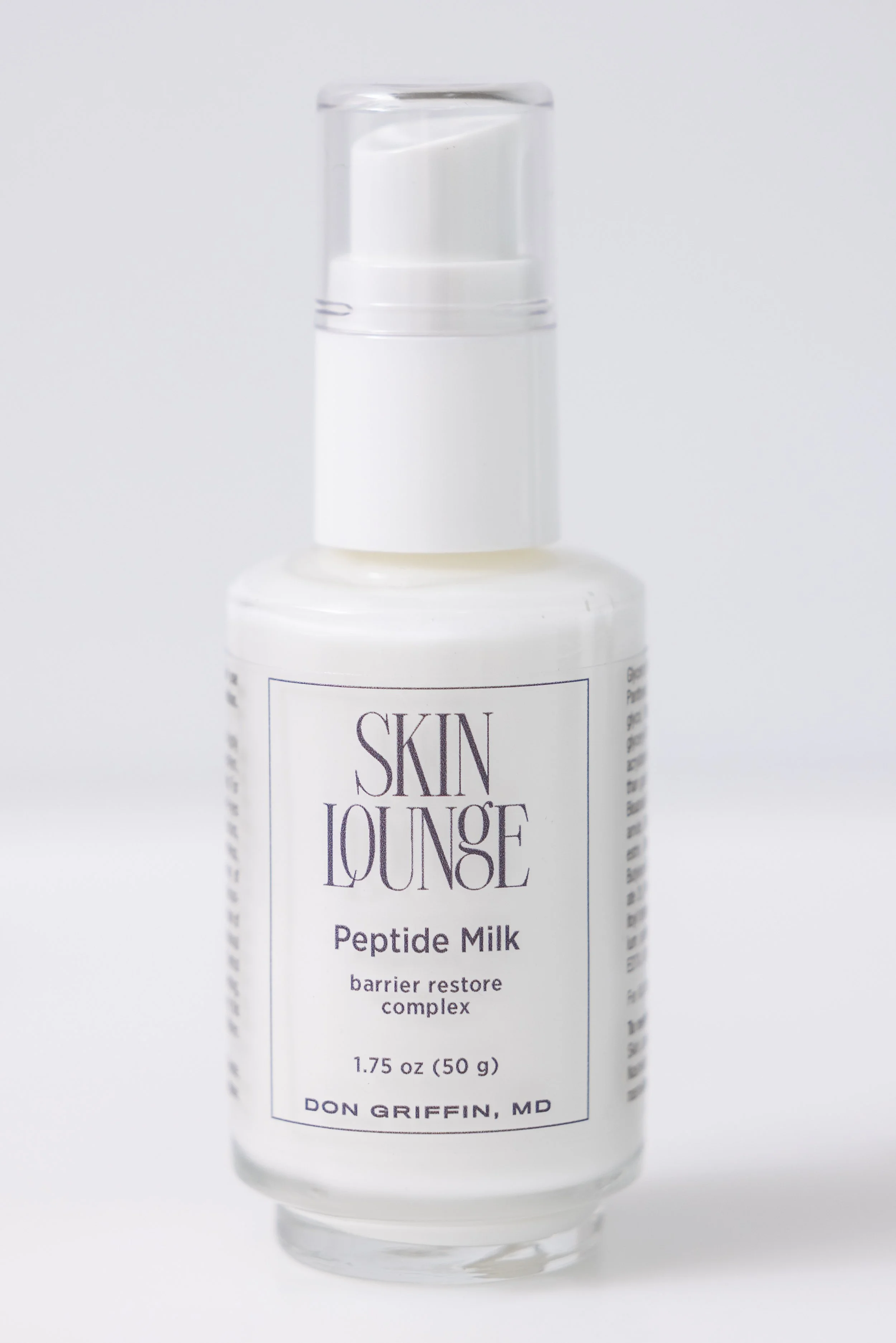 White pump bottle of Skin Lounge Peptide Milk barrier restore cream on a white background.