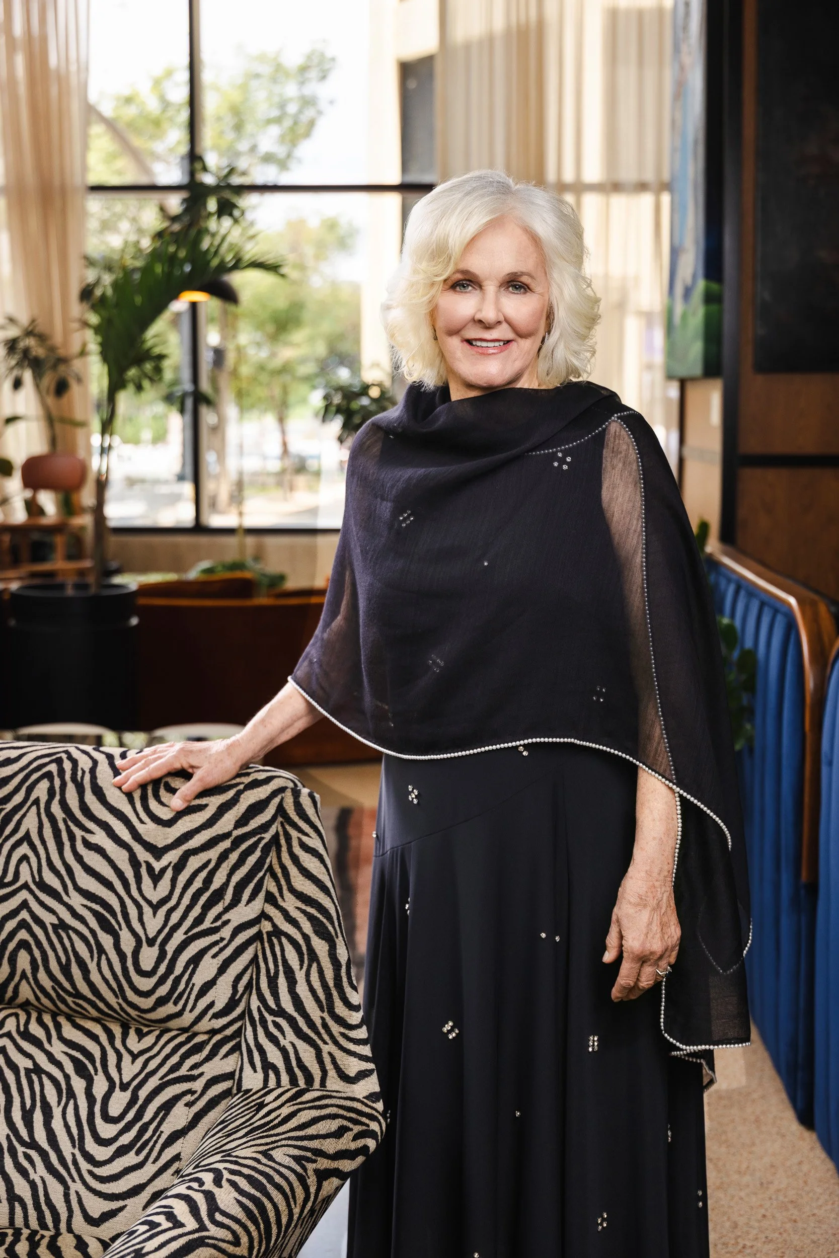 Trish Munro in a black beaded shawl, standing beside a zebra print chair for her Nashville editorial portrait.