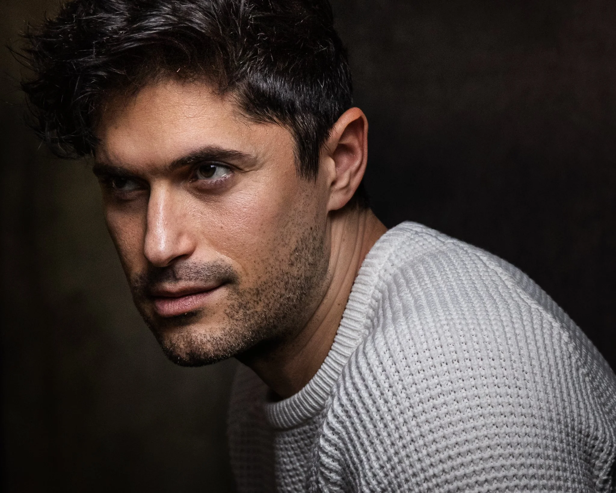 Dramatic close-up portrait of man against dark background showing emotion and depth, photographed by Nashville headshot photographer
