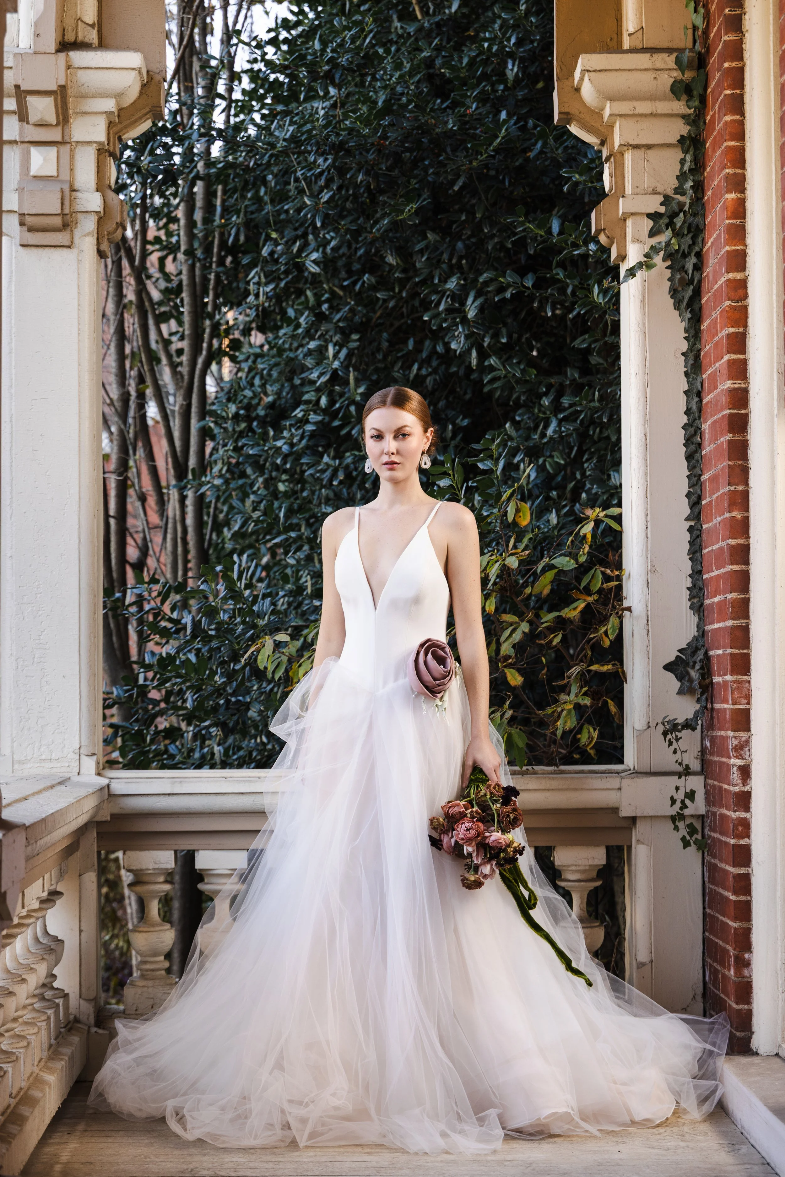 Bride in a floral textured gown standing outside the Watson House with soft natural light and subtle warm glow from added indoor strobe