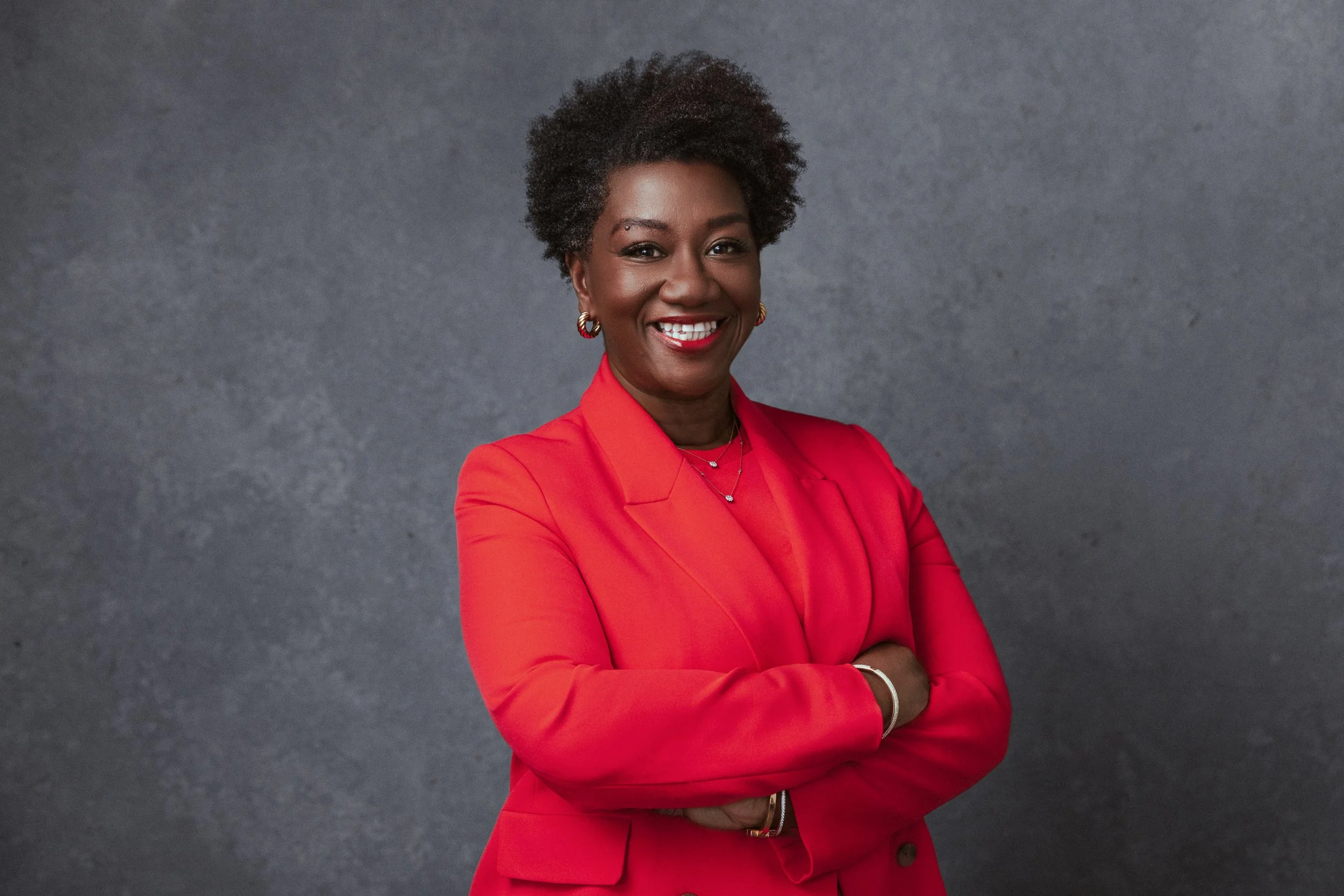 This power pose softened by a genuine smile showcases balance—polish with warmth. A clean studio backdrop and bold color make this a go-to portrait from a Nashville Headshot Photographer.