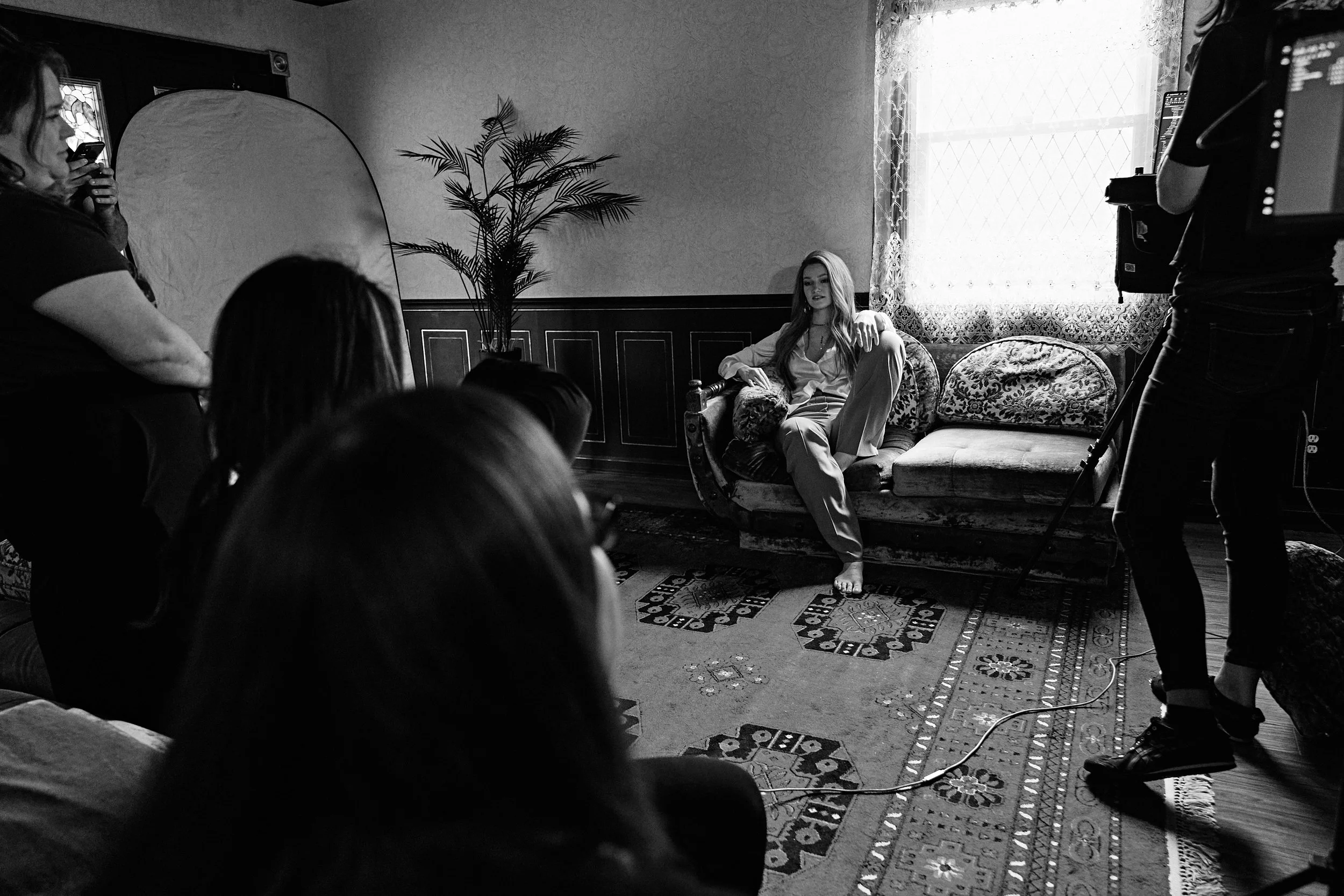 Behind the scenes of a professional headshot session in Nashville with photographer Tausha Dickinson directing a client on a vintage couch with studio lighting