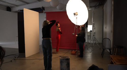 Behind the scenes of a studio portrait session using a large octobox and red backdrop