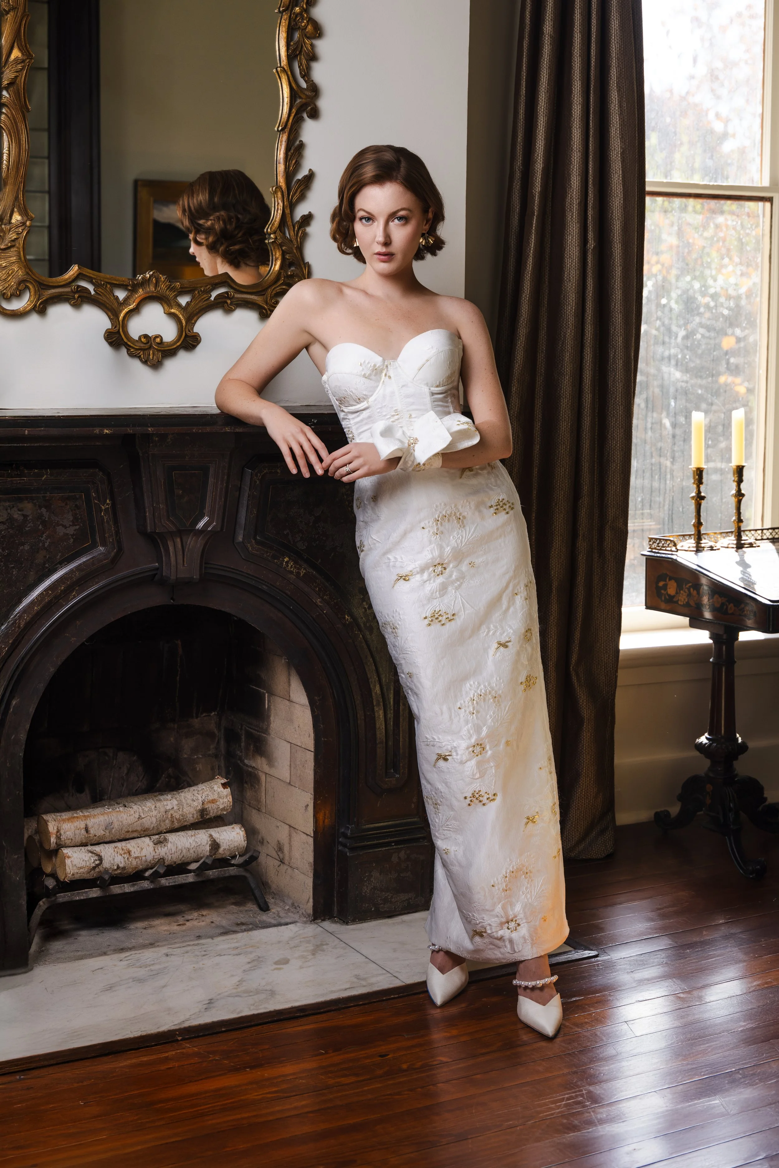 Bride in strapless embroidered jacquard gown leans on vintage fireplace in romantic Nashville editorial setting