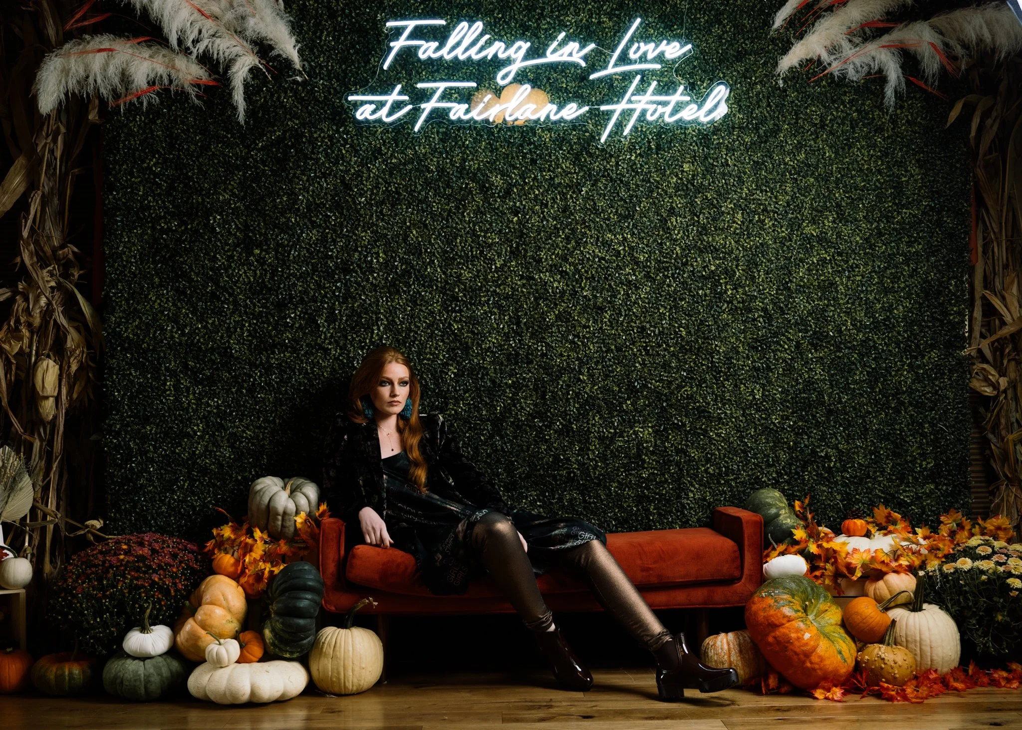 Fashion editorial portrait at Fairlane Hotel in Nashville featuring a red-haired model seated on an orange sofa surrounded by pumpkins and fall decor