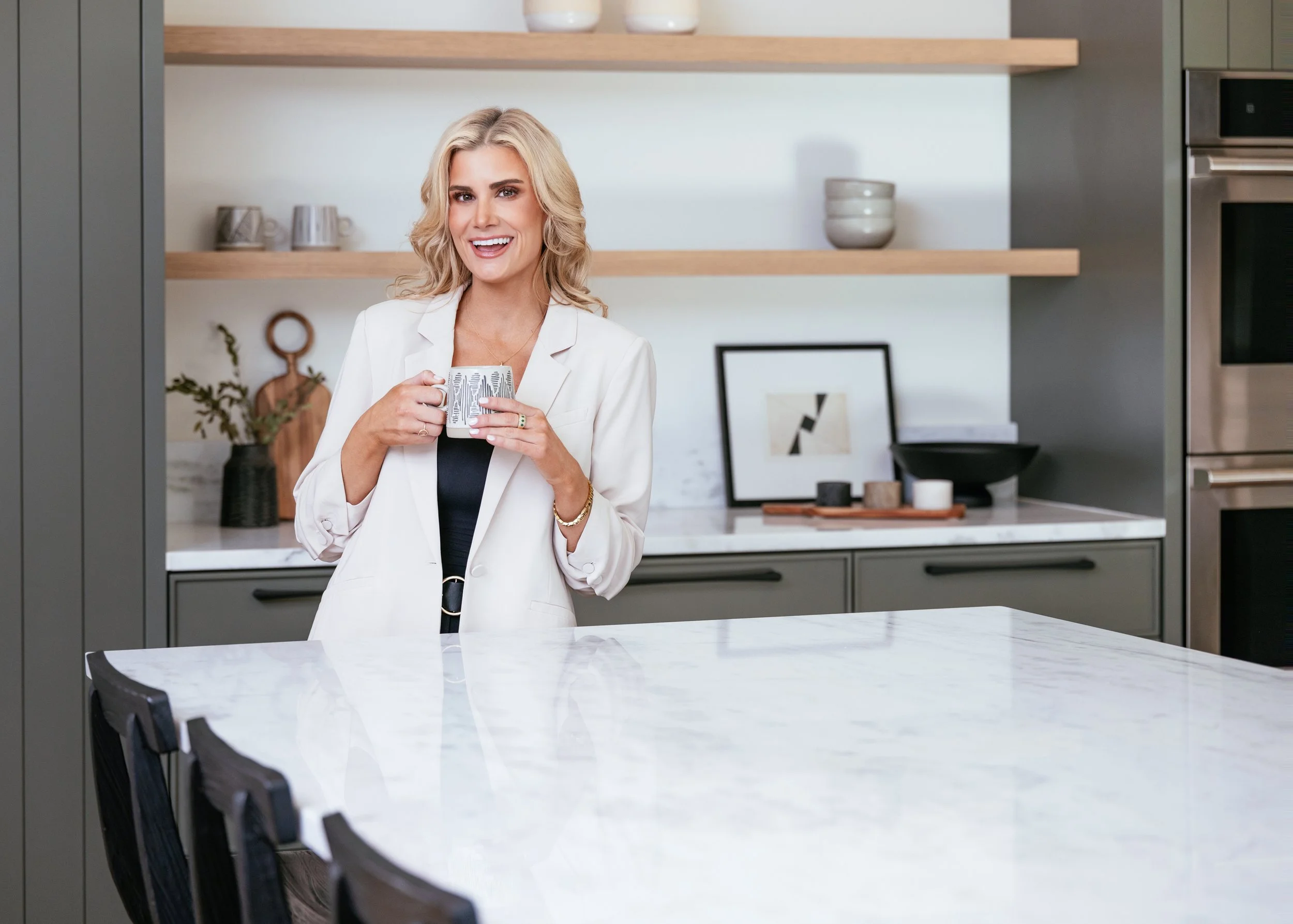 Female entrepreneur holding a coffee mug in a modern kitchen during a Nashville branding photography session.
