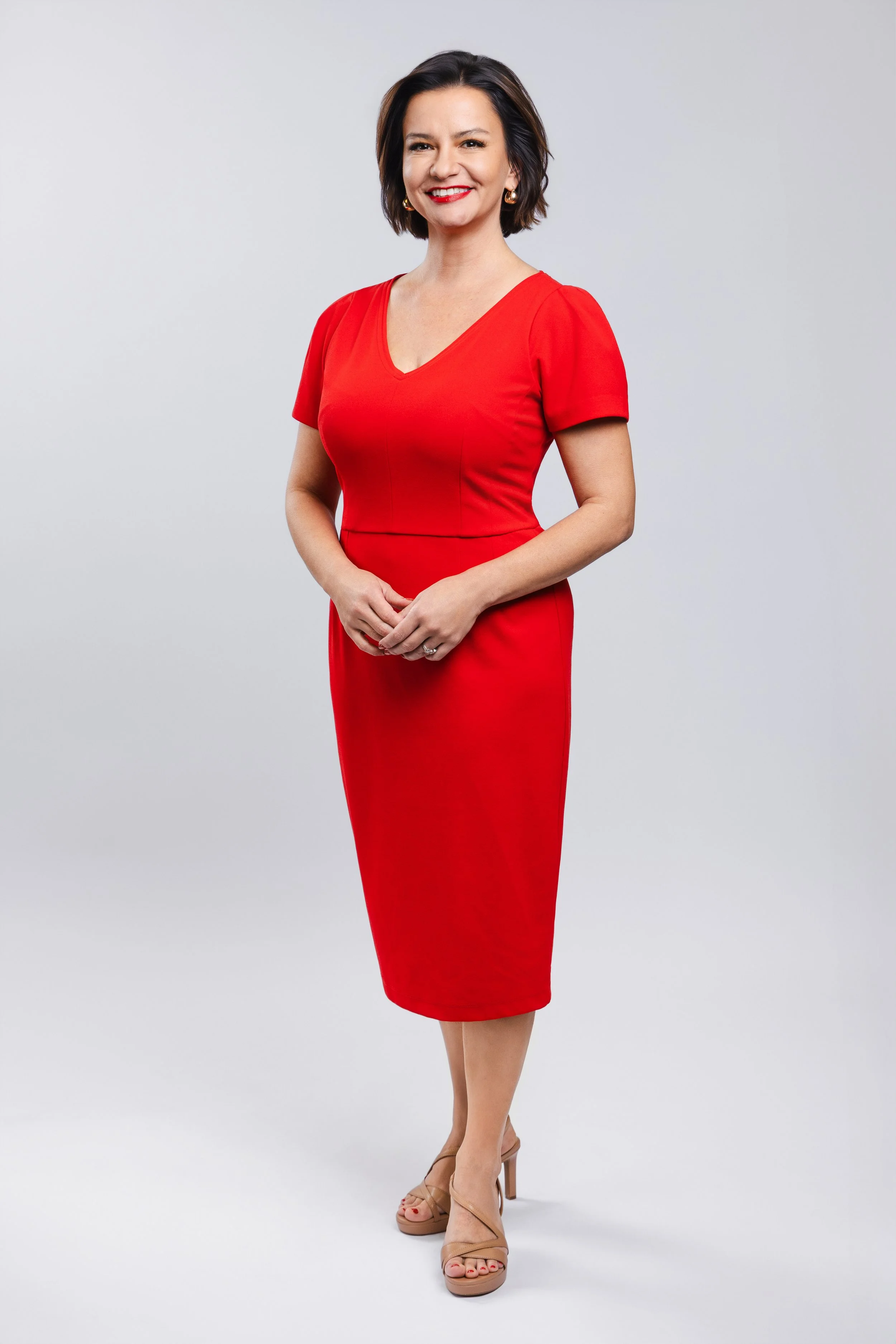 Full-body studio portrait of a female WSMV news anchor wearing a red dress, photographed by Tausha Dickinson.