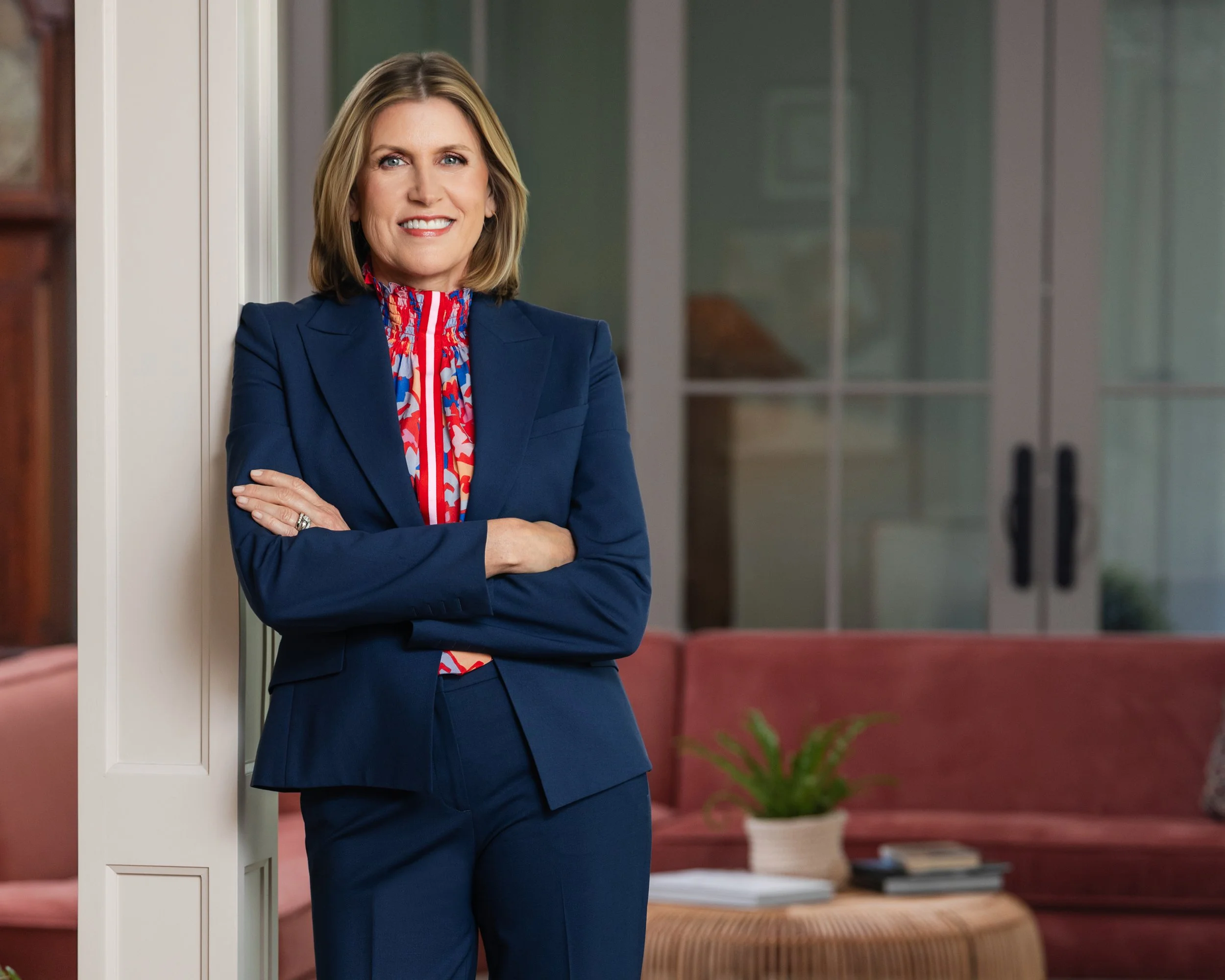 Polished executive headshot of woman in navy suit with colorful scarf standing confidently in professional indoor setting, Nashville TN