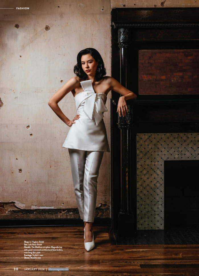 An editorial image featuring a sleek white jumpsuit with architectural bow detailing, set against an industrial-chic backdrop. Nashville Fashion Photographer specializing in contemporary bridal fashion photography for editorial publications.